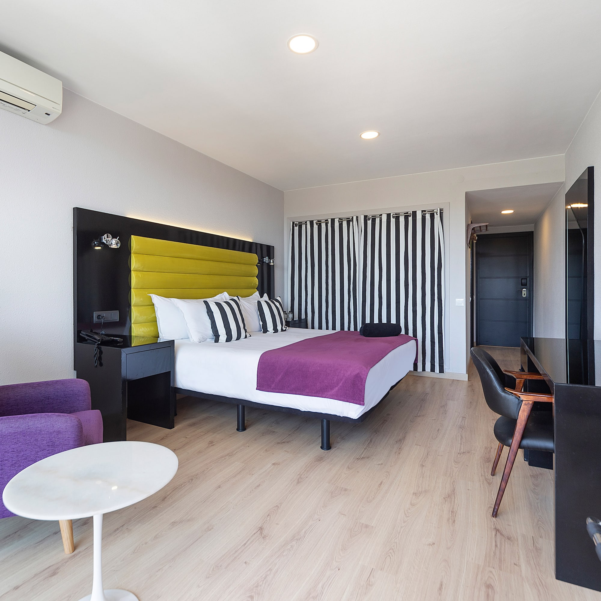 a room with a bed and purple chairs