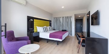 a room with a bed and purple chairs