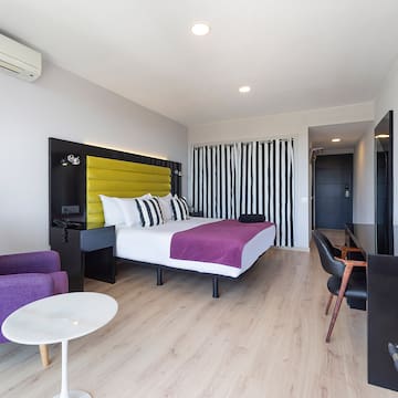 a room with a bed and purple chairs