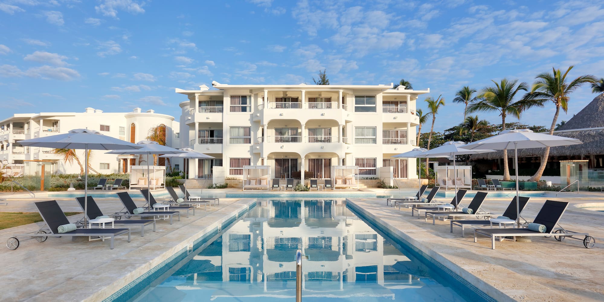 a pool with lounge chairs and umbrellas in front of a building