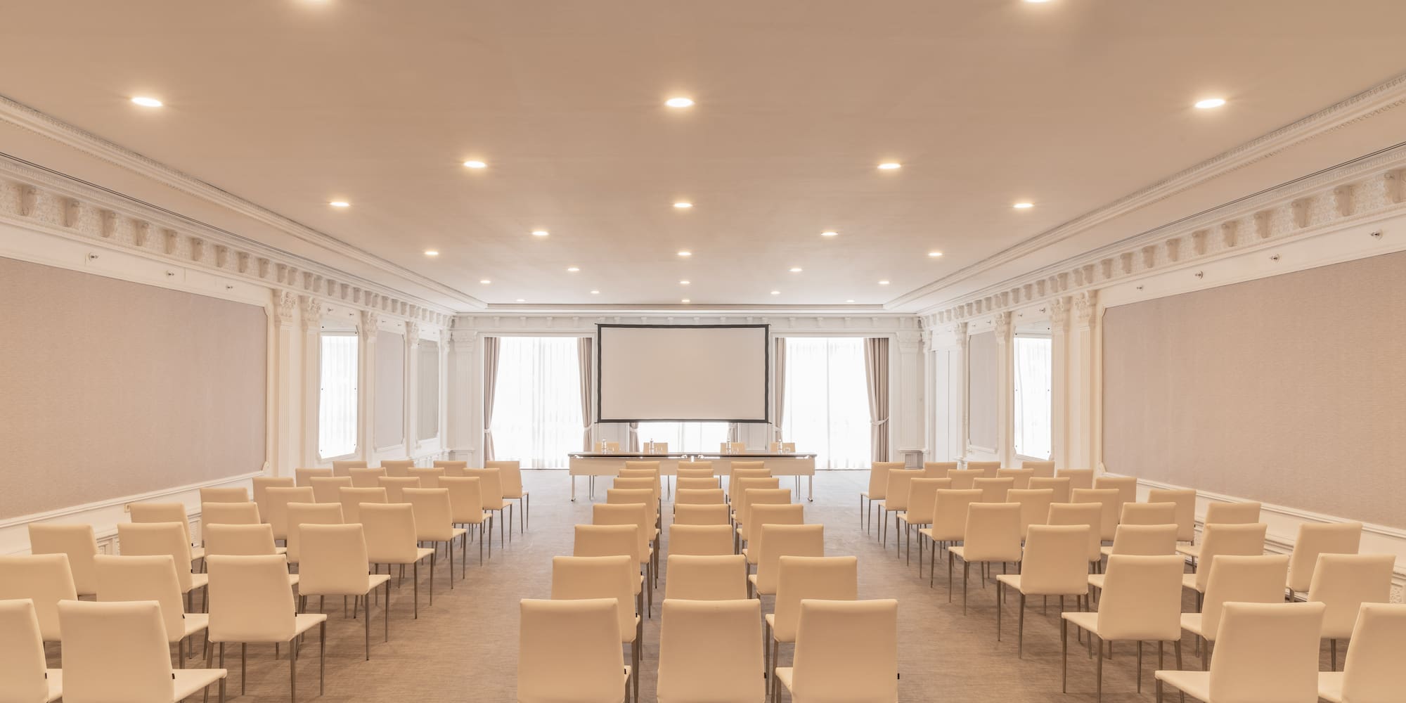 Elegant conference room with rows of chairs and a large projection screen.
