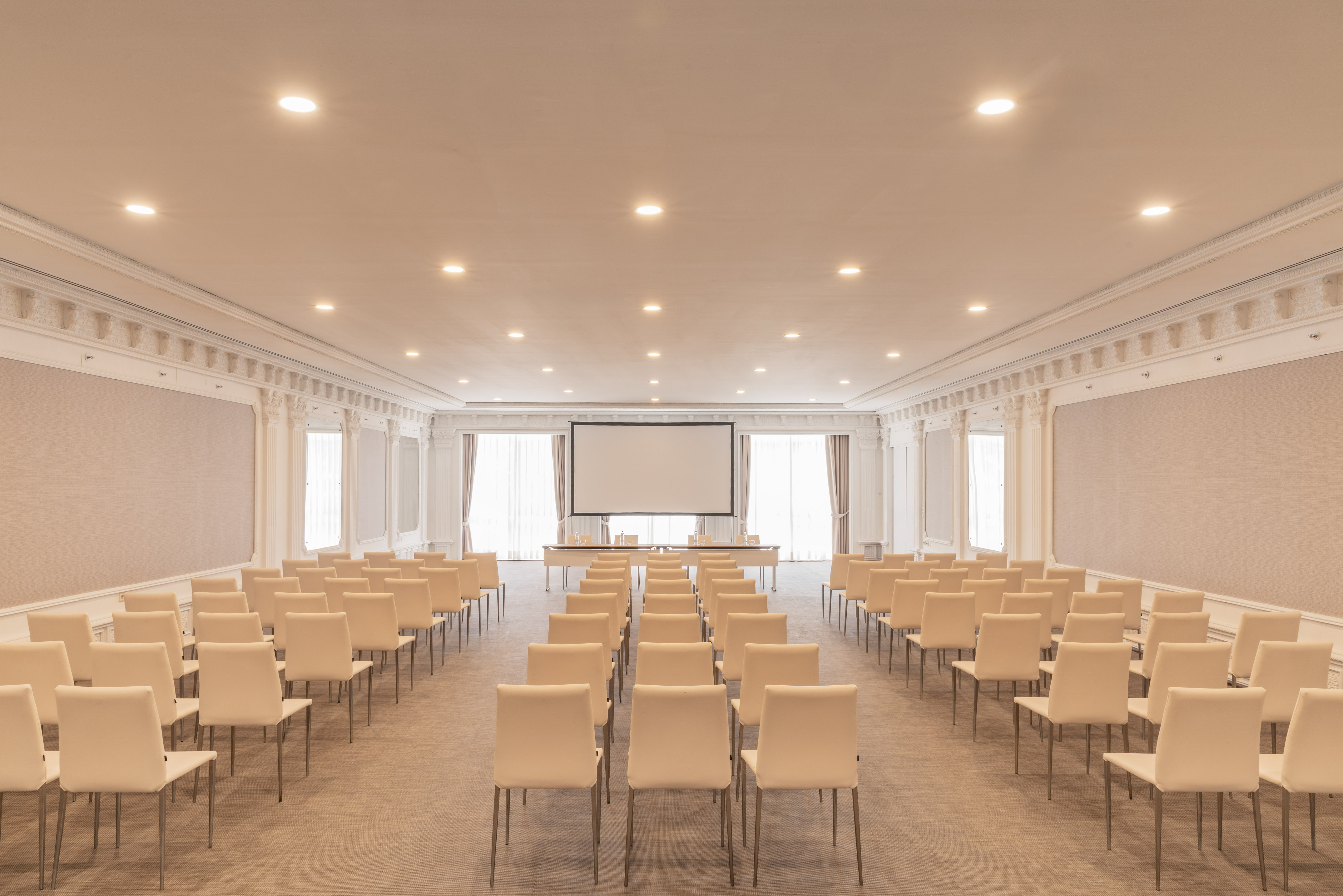 Elegant conference room with rows of chairs and a large projection screen.