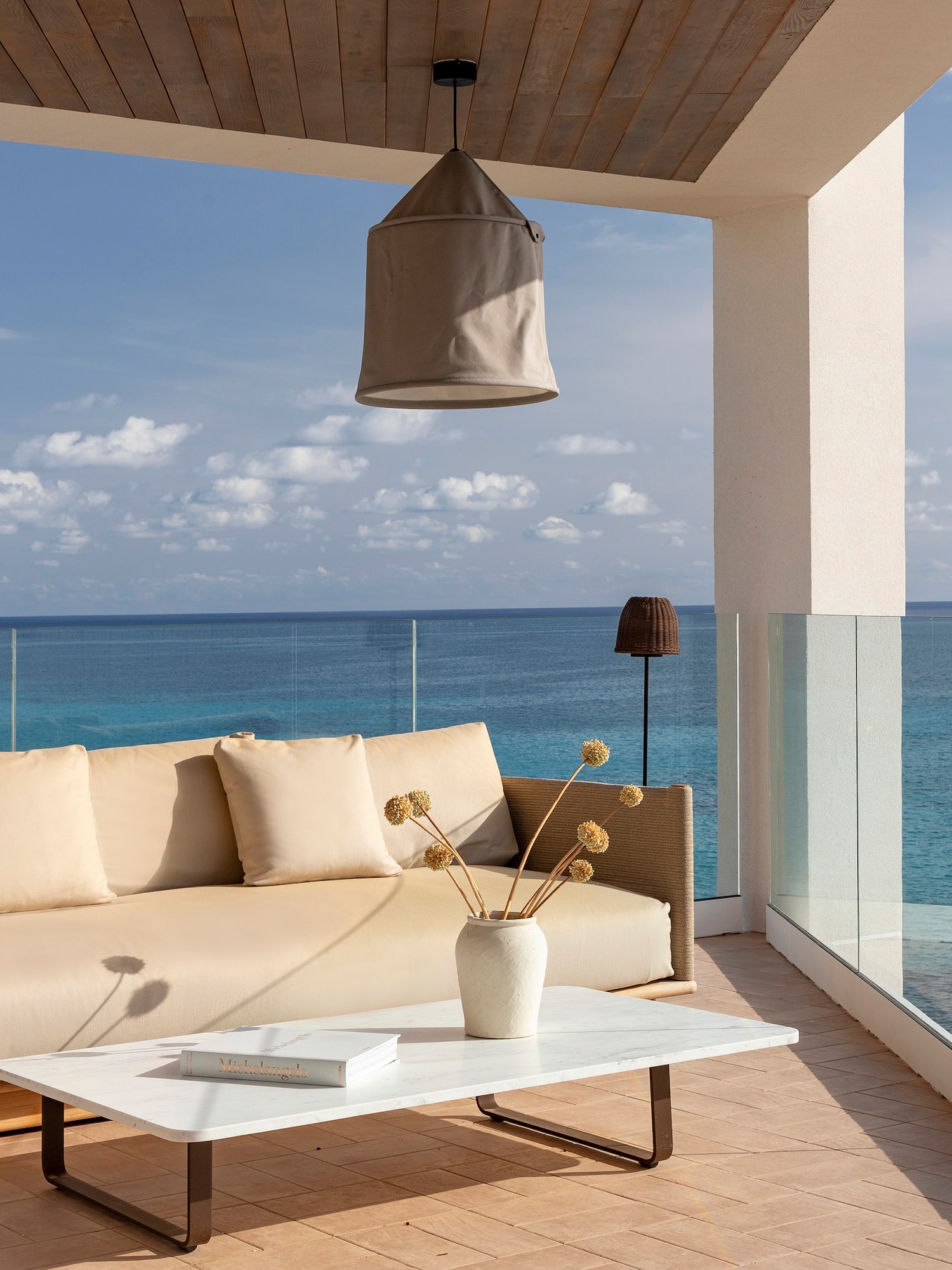 a couch and coffee table on a deck overlooking the ocean