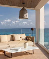 a couch and coffee table on a deck overlooking the ocean