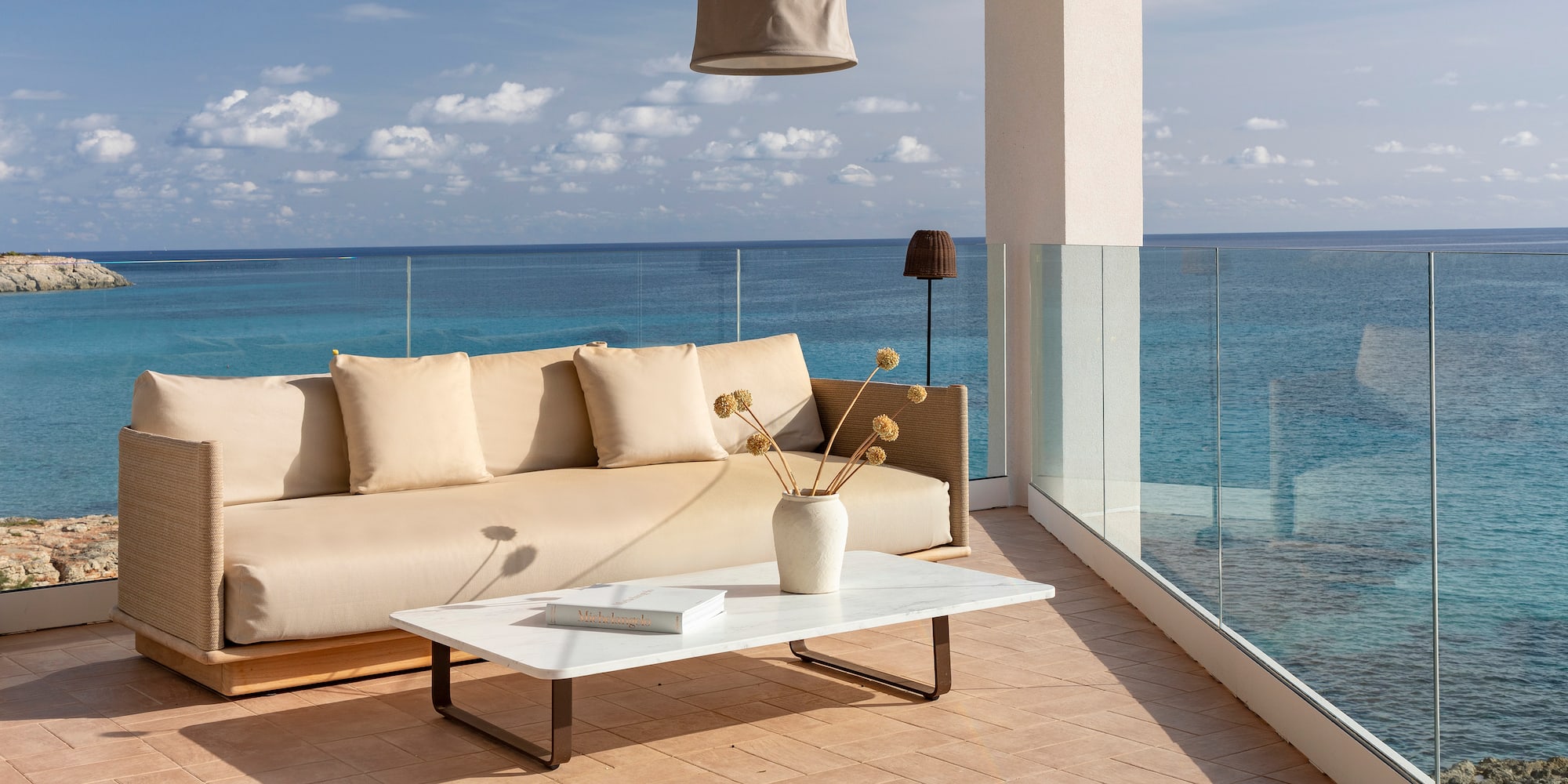 a couch and coffee table on a deck overlooking the ocean