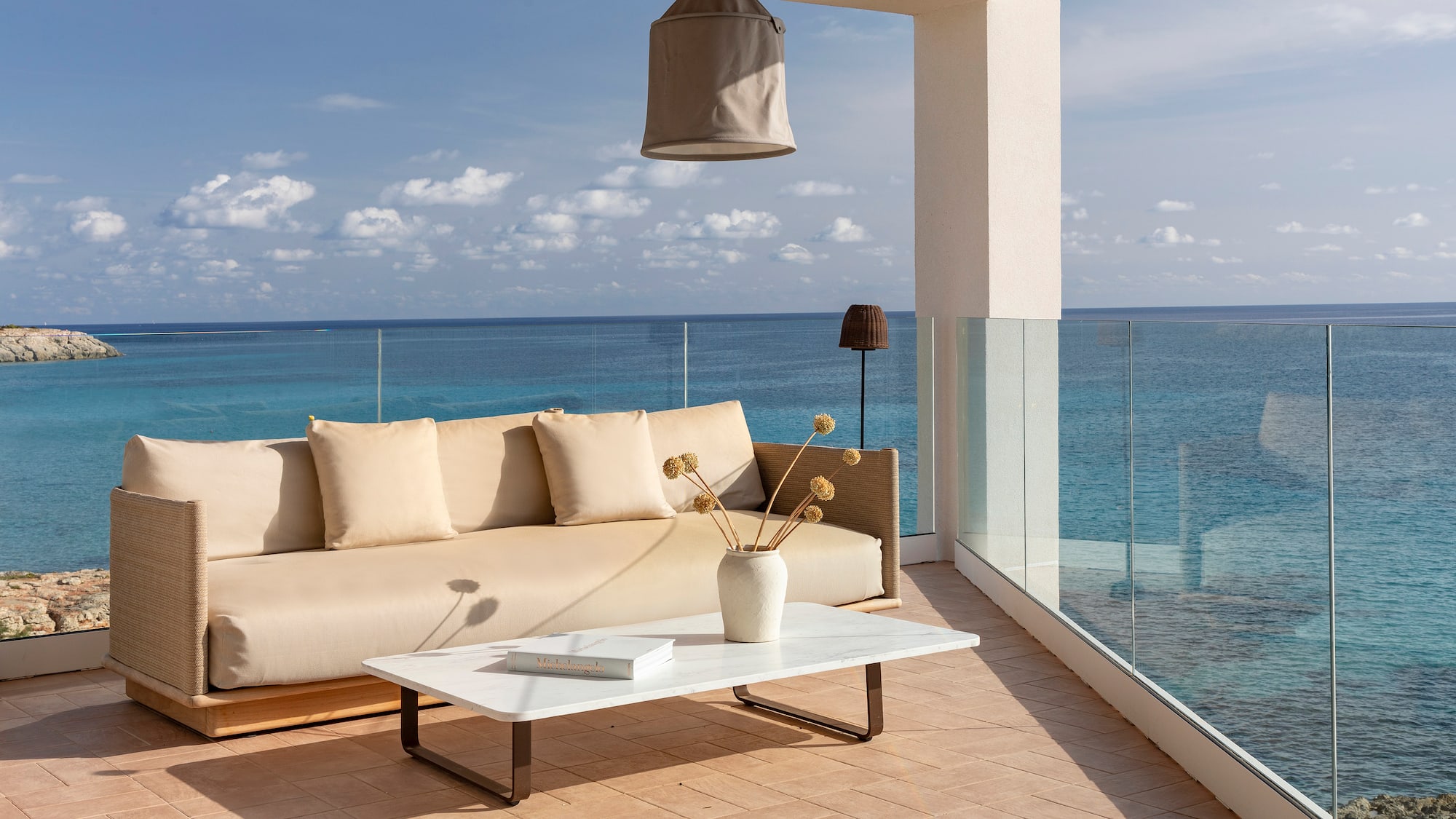 a couch and coffee table on a deck overlooking the ocean