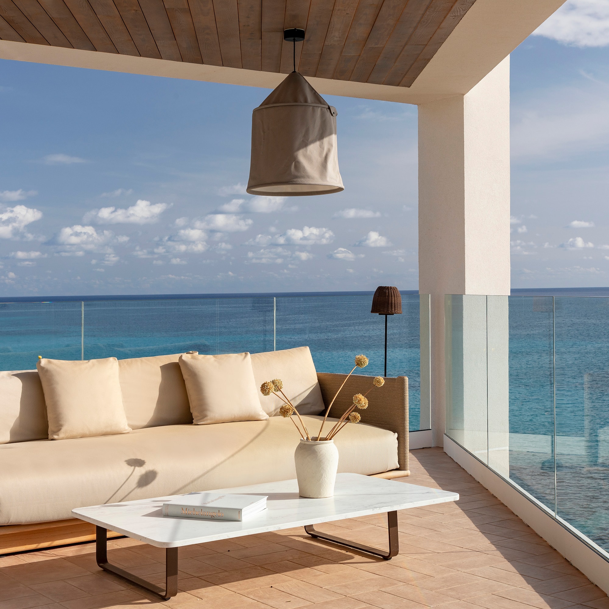 a couch and coffee table on a deck overlooking the ocean