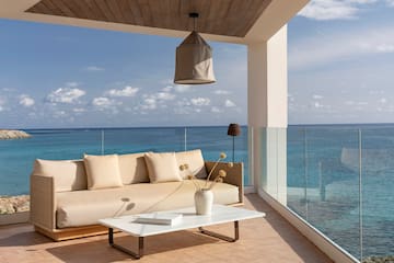 a couch and coffee table on a deck overlooking the ocean