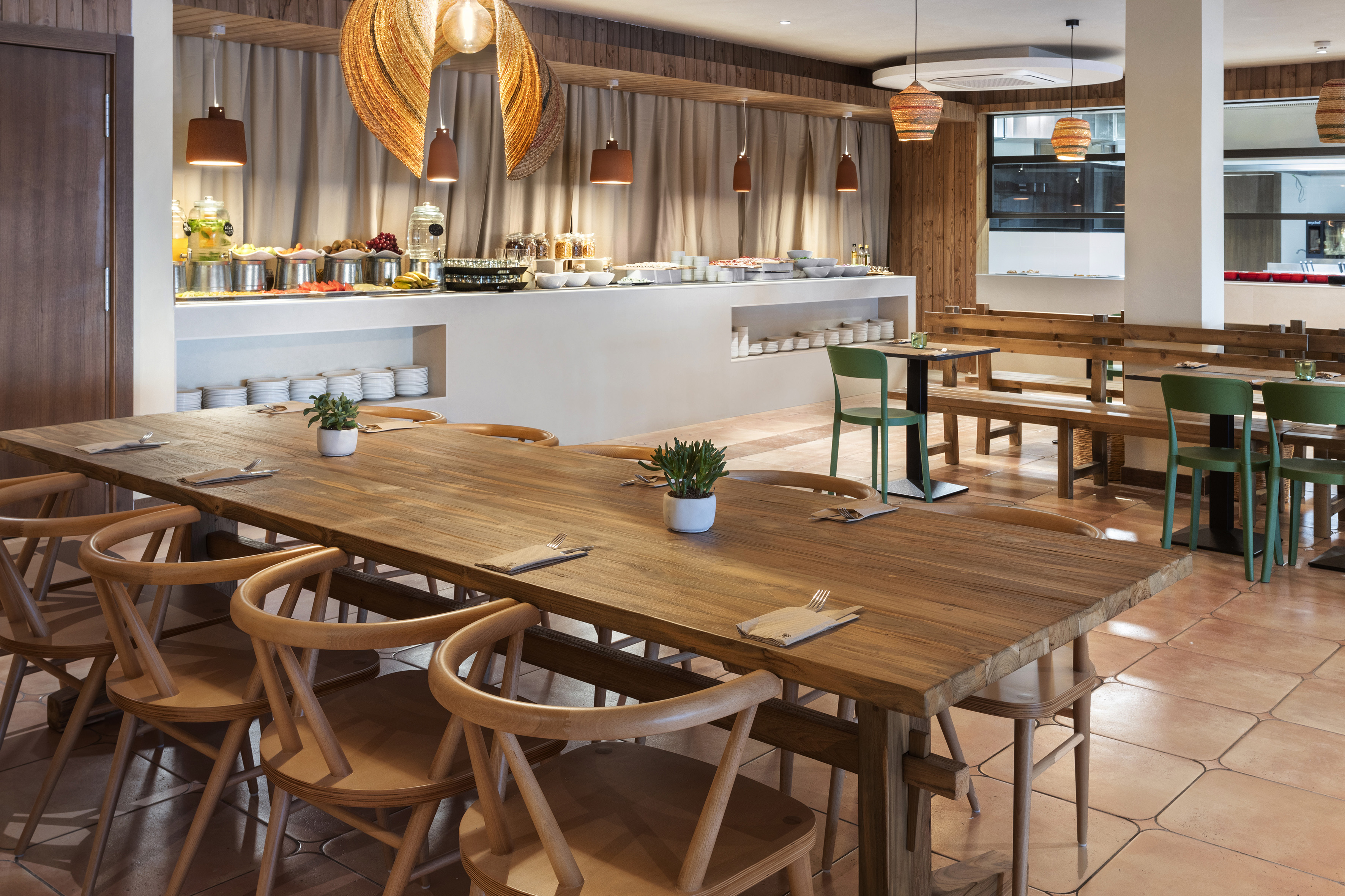 Restaurant dining area with buffet, long wooden tables, and natural wood decor.