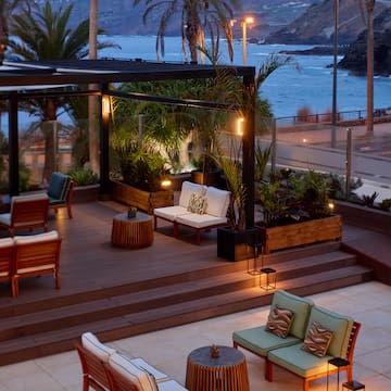 a patio with chairs and tables and a view of the ocean
