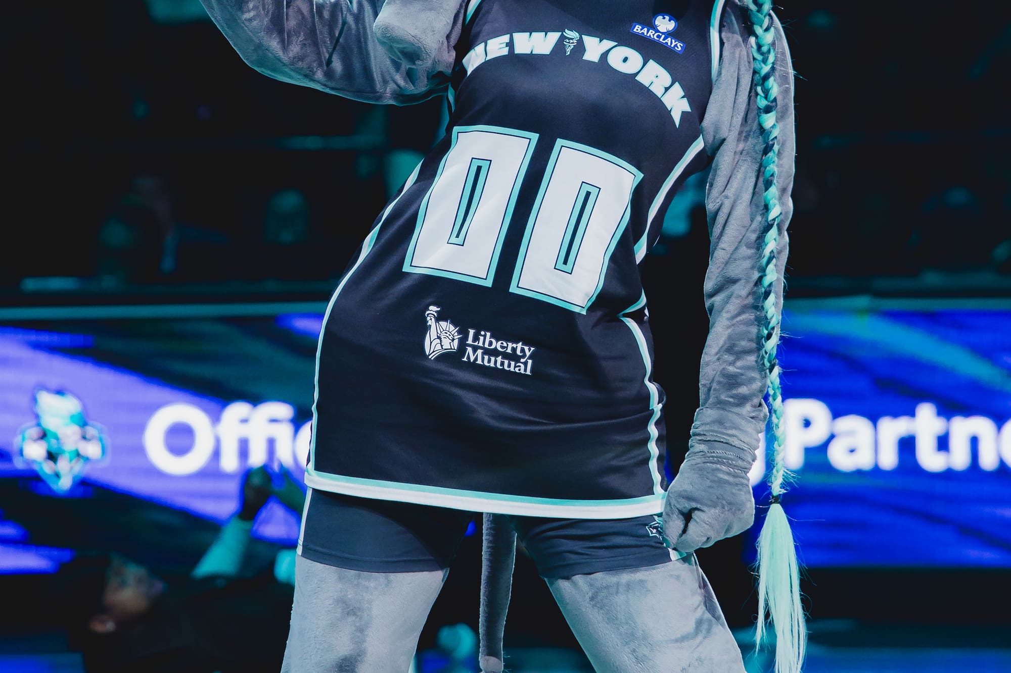 New York Liberty elephant mascot in jersey with Liberty crown, holding fan.