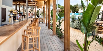 a wooden patio with chairs and a pool in the background