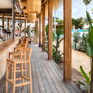 a wooden patio with chairs and a pool in the background