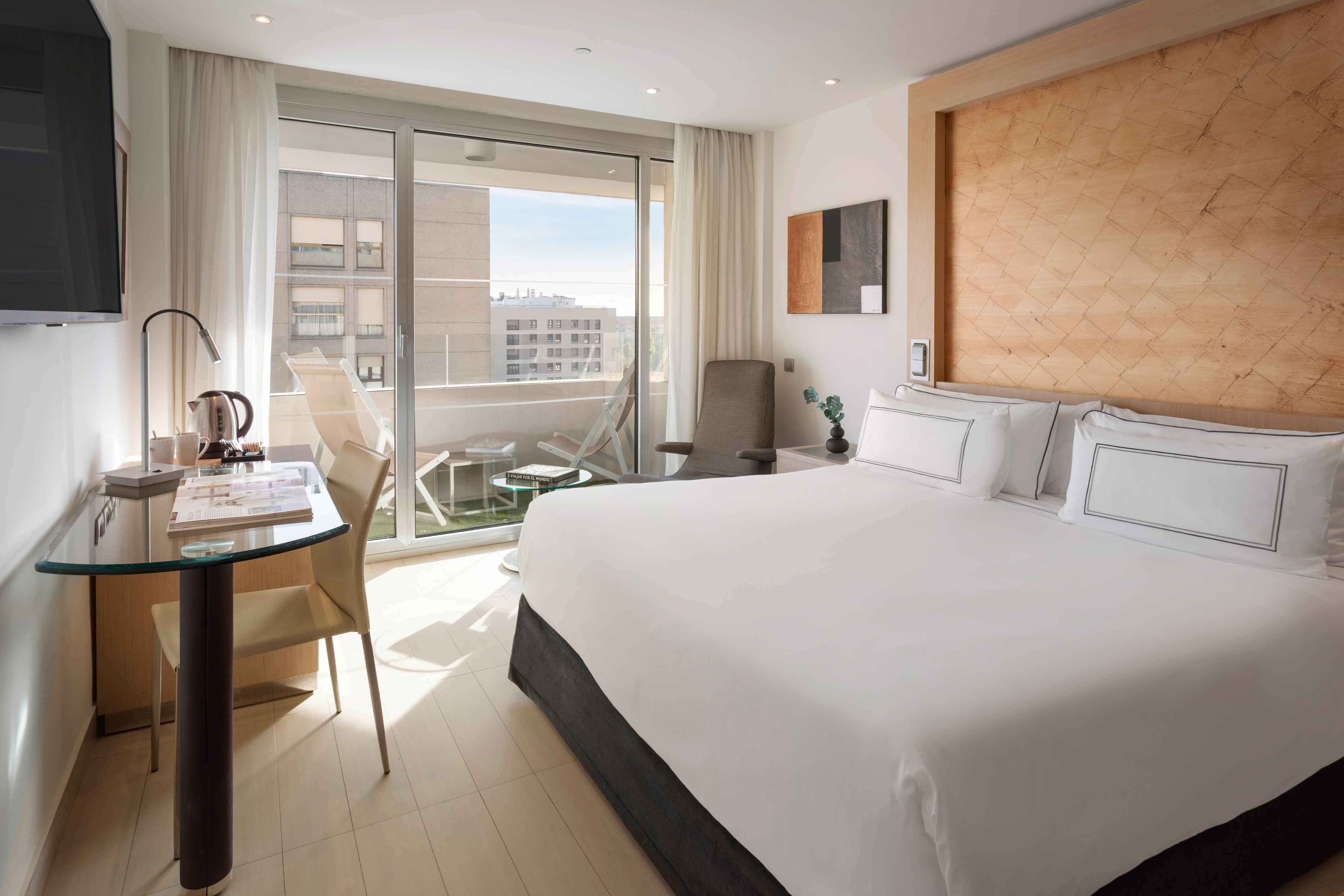 Luxury hotel bedroom with king bed, wooden headboard, and balcony.