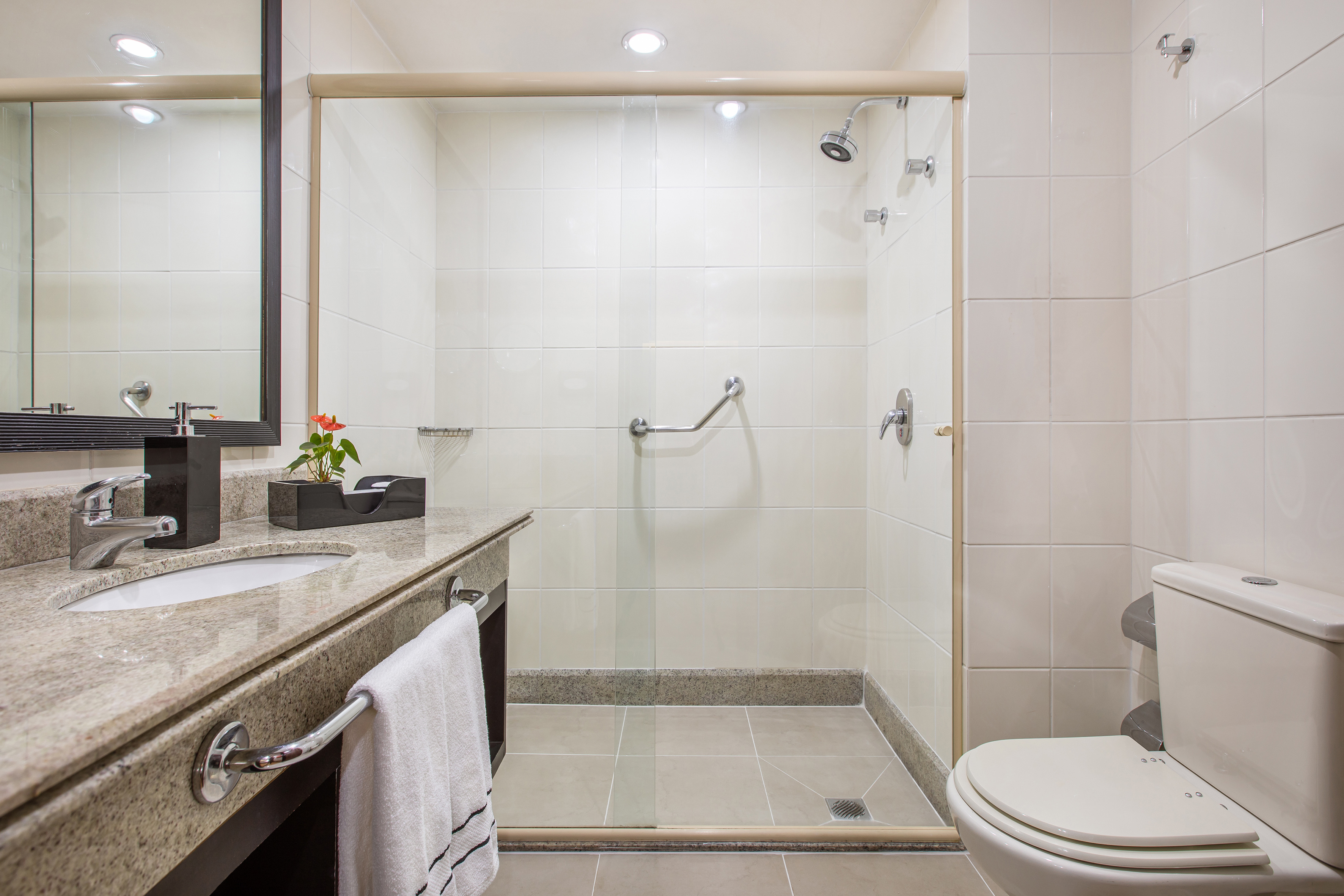 Accessible bathroom with glass shower, grab bar, modern vanity, and toilet.