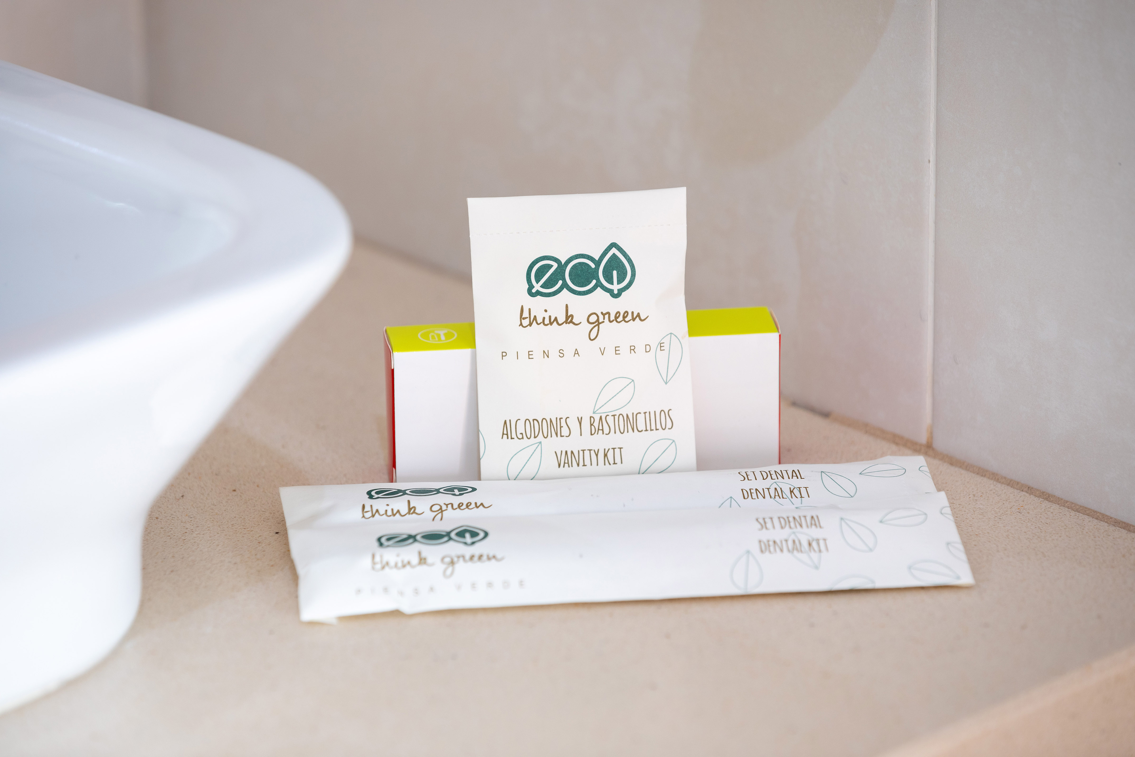 Eco-friendly hotel bathroom vanity and dental kits on counter.