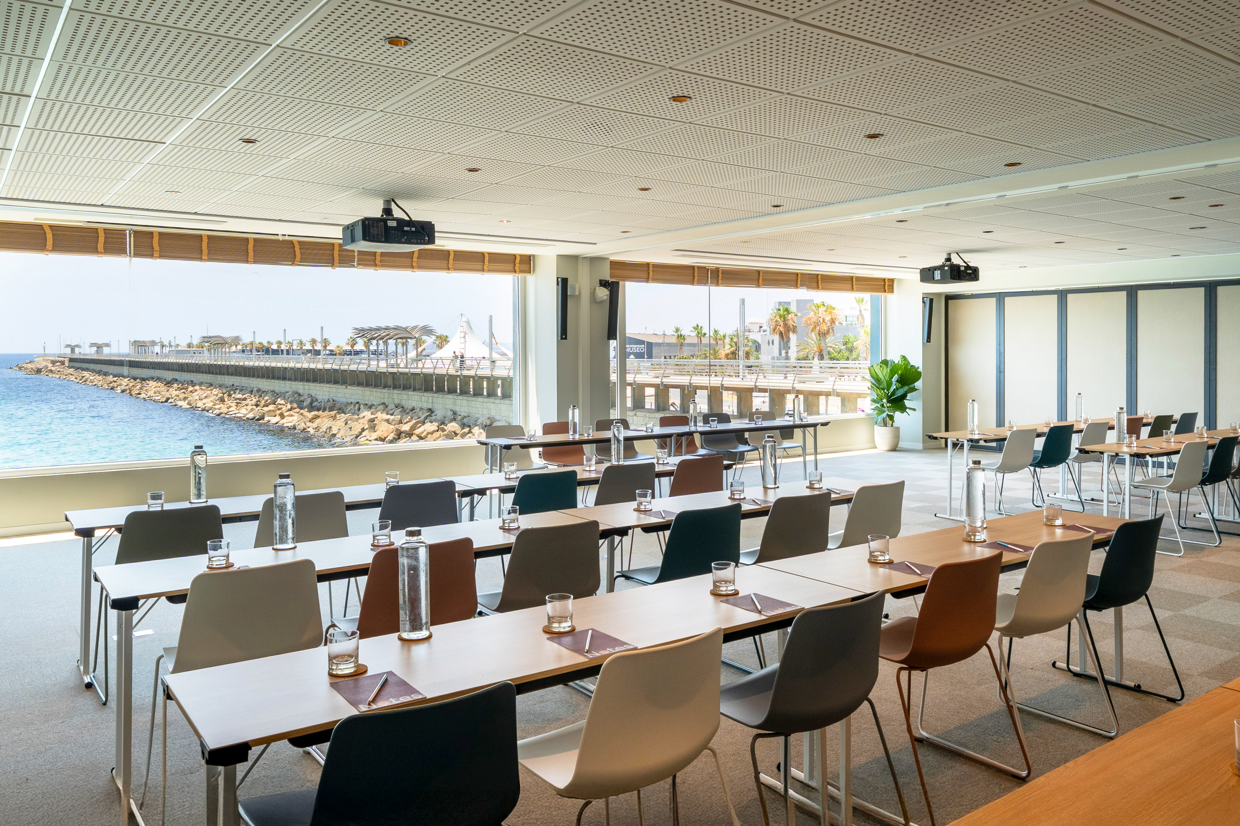 Modern meeting room with ocean view, conference tables, and projectors.
