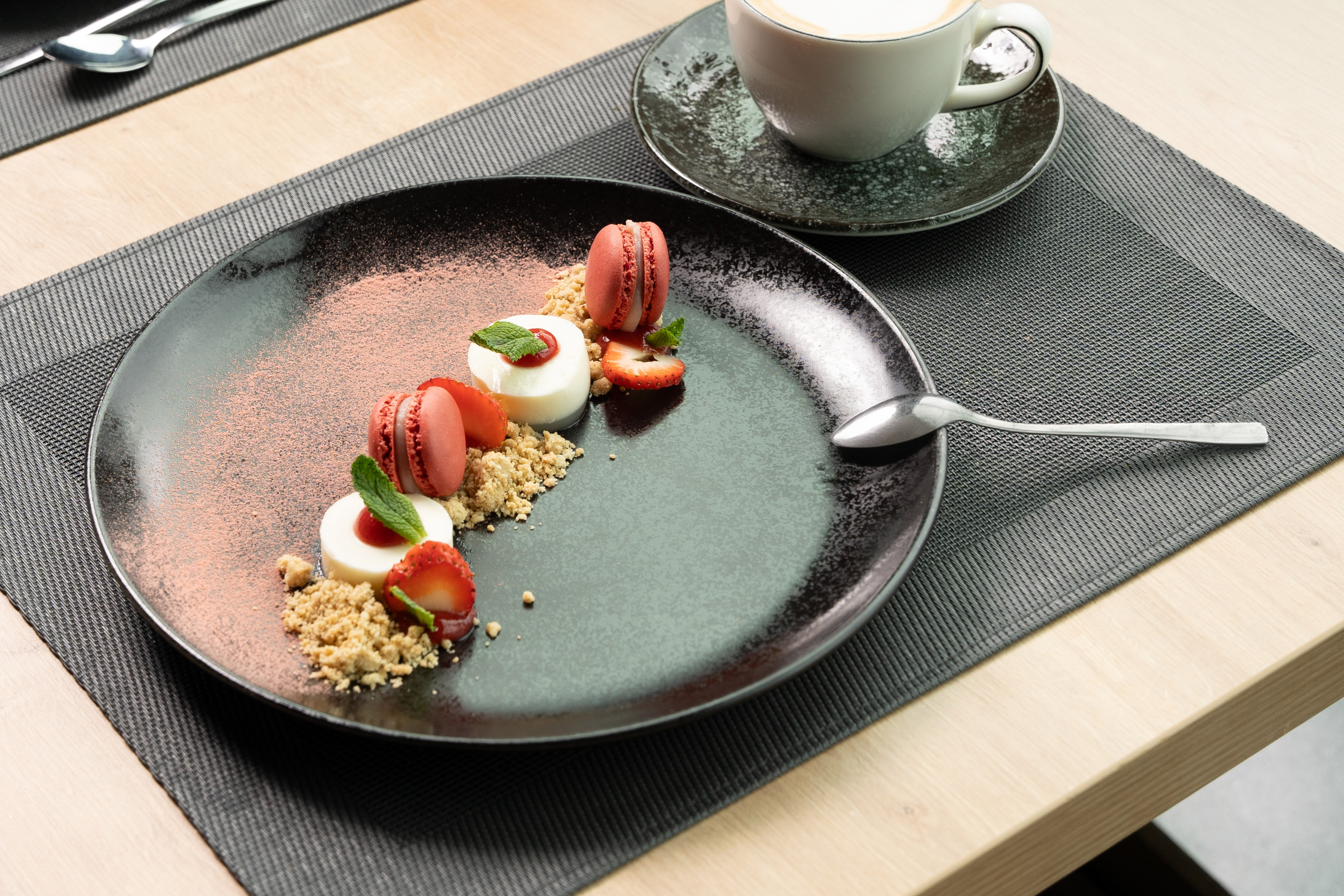 Panna cotta dessert with red macarons, strawberries, and coffee.