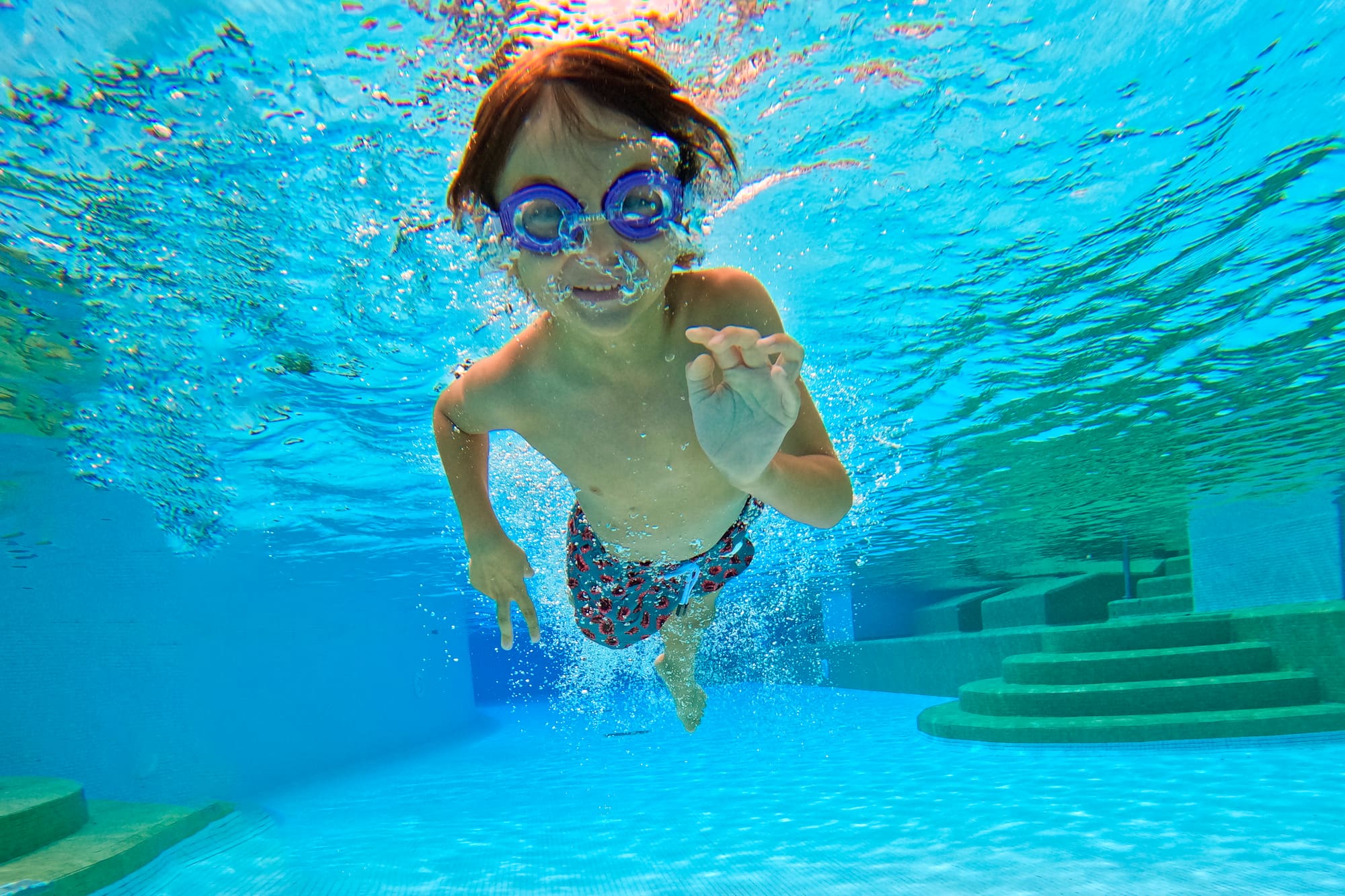 a boy swimming underwater in a pool