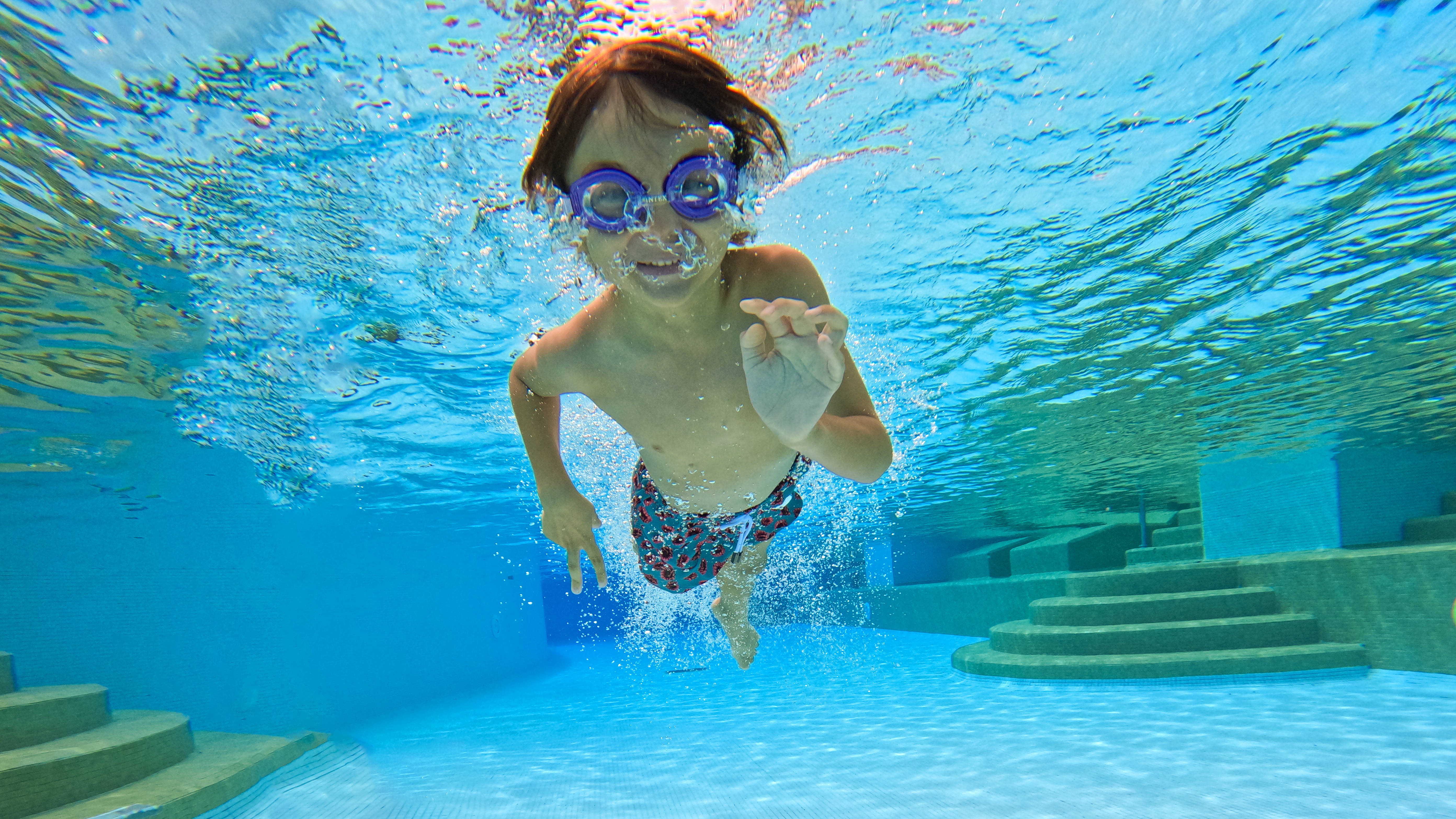 a boy swimming underwater in a pool