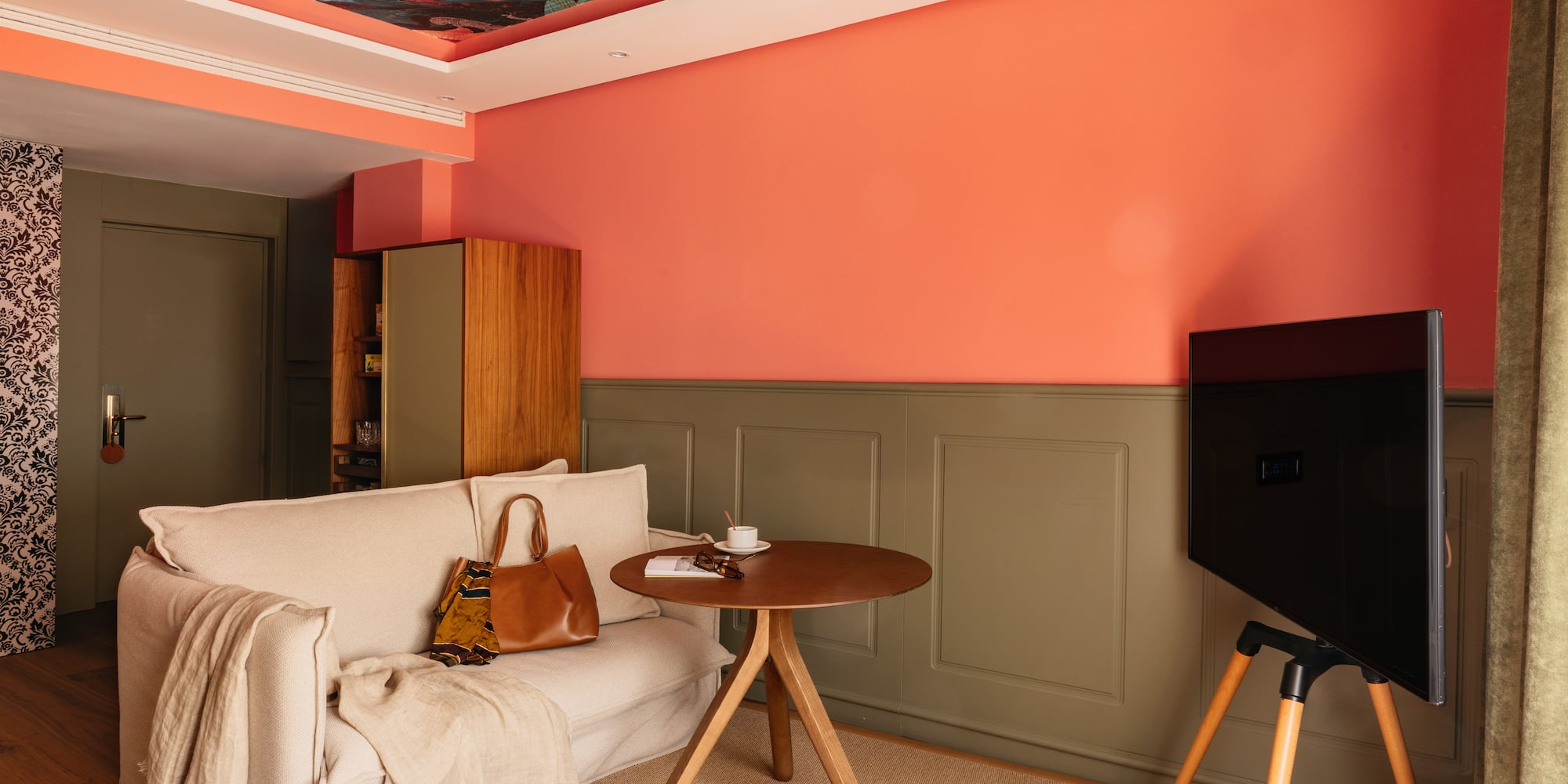 Sala de estar moderna: paredes salmón, sofá beige, TV y techo botánico.