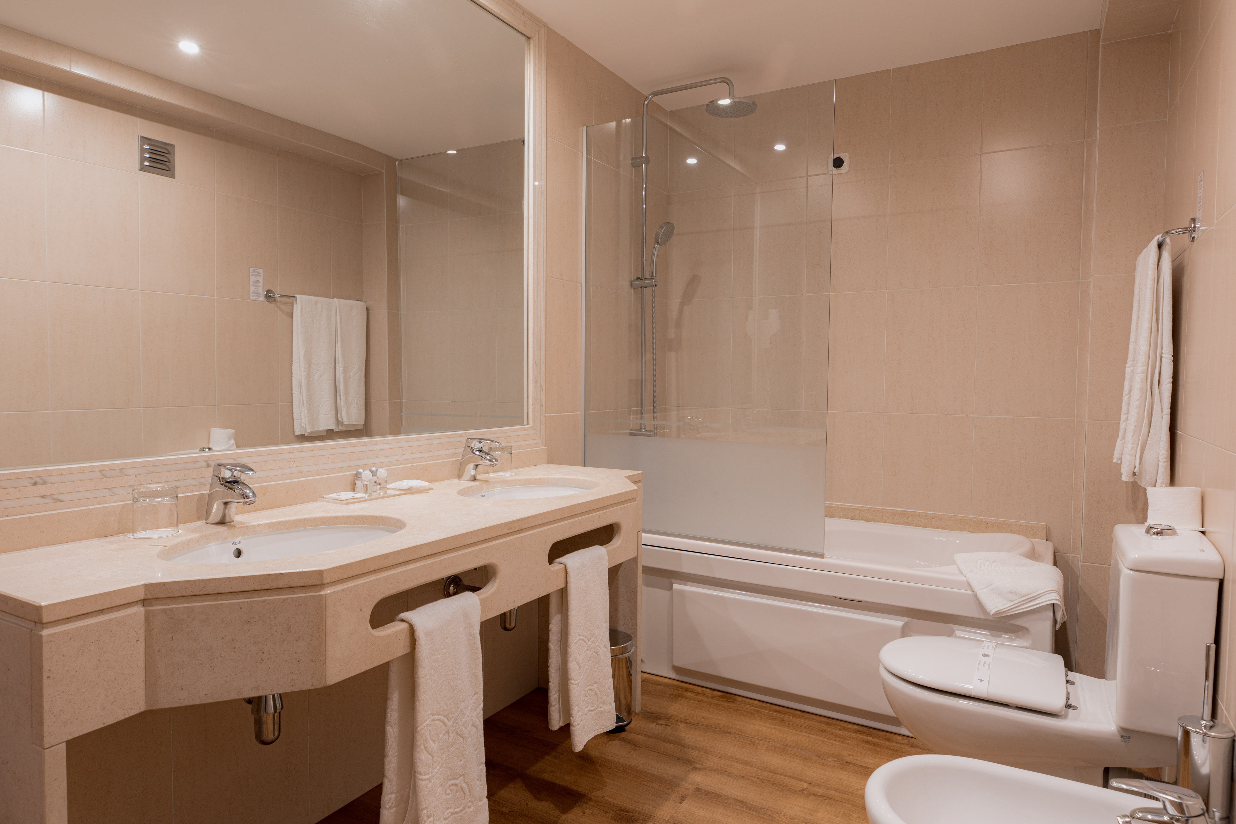 Hotel bathroom: double vanity, bathtub with shower, toilet, bidet.