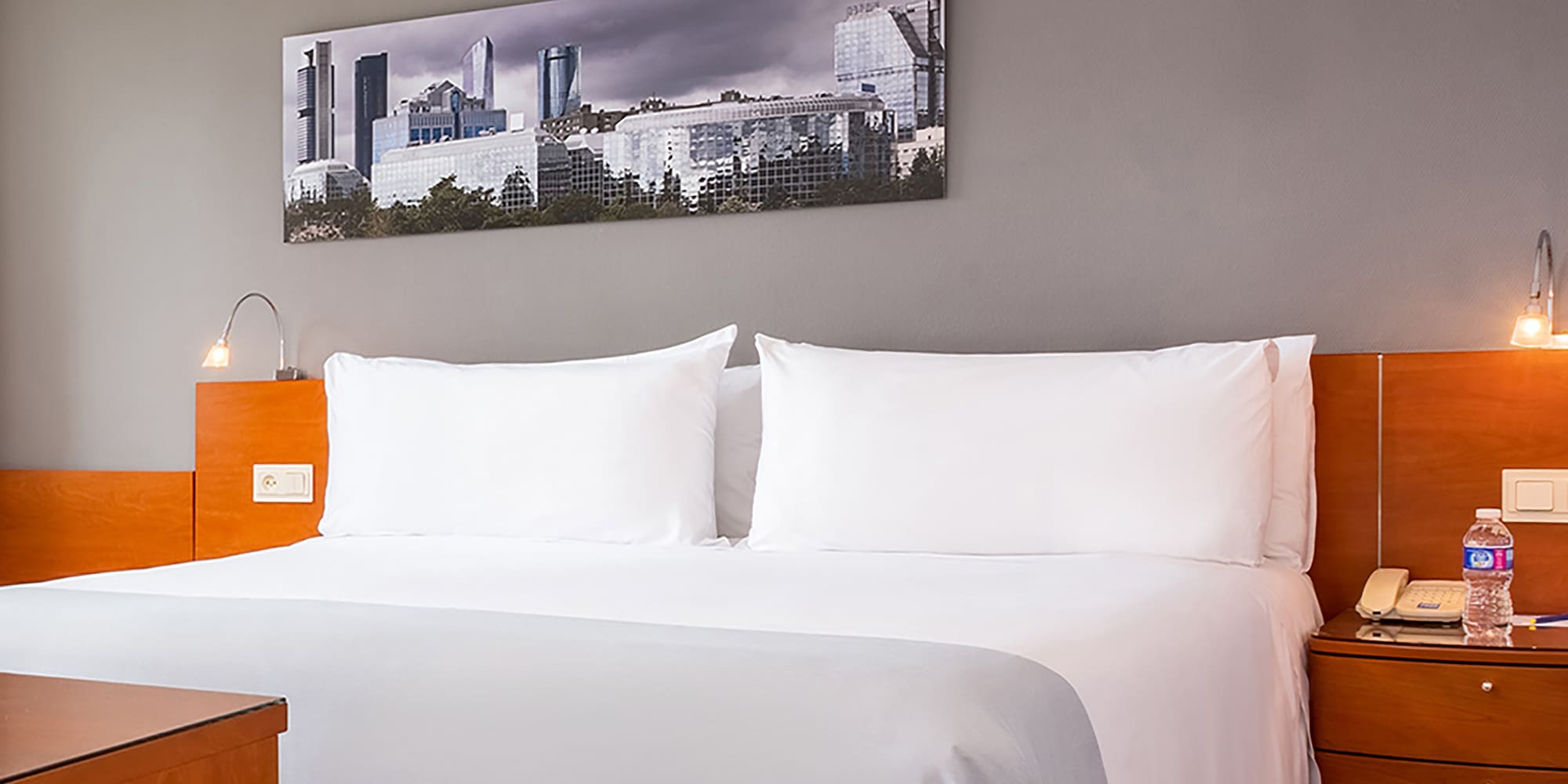 a bed with white sheets and a wood headboard