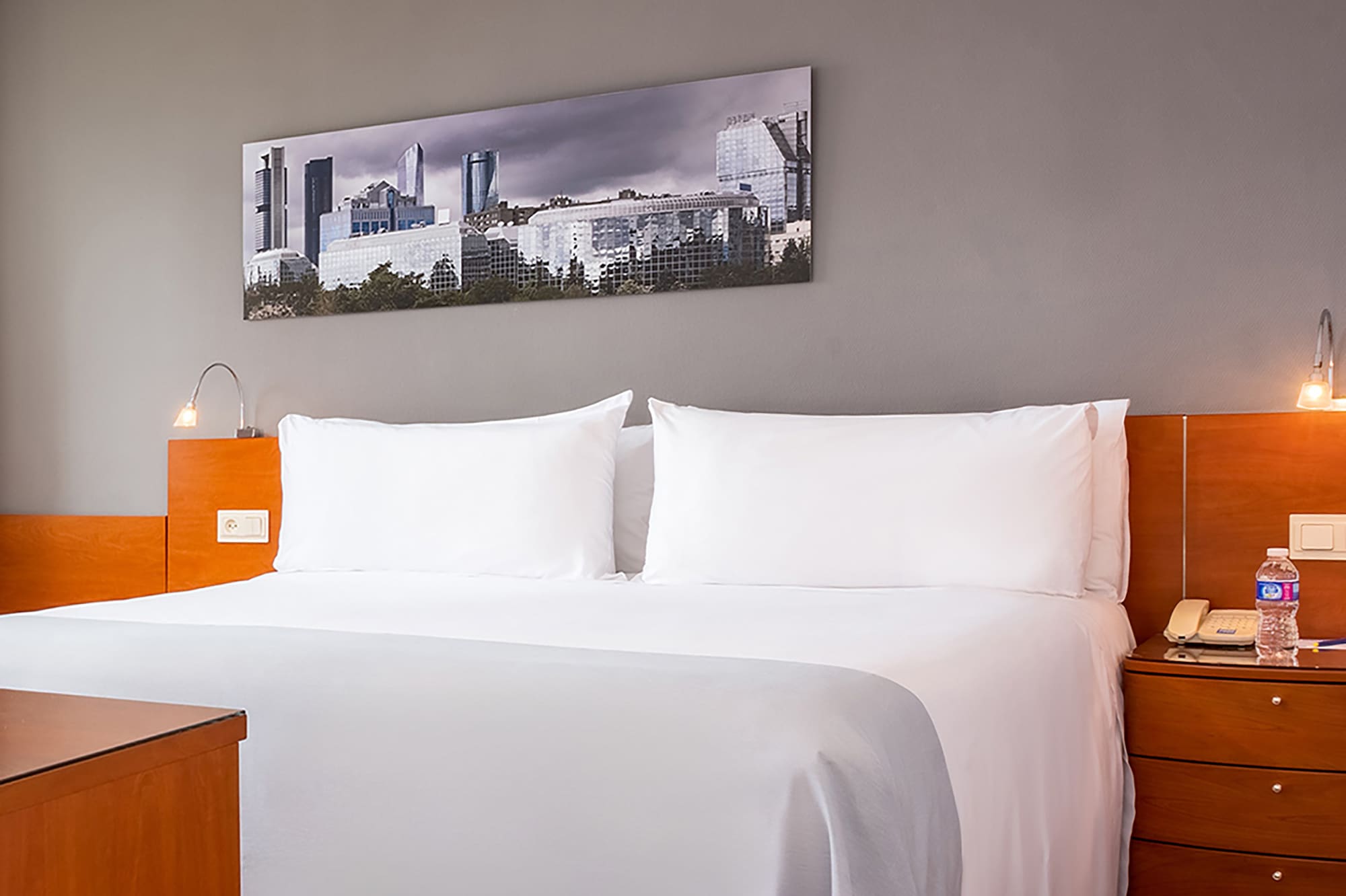 a bed with white sheets and a wood headboard