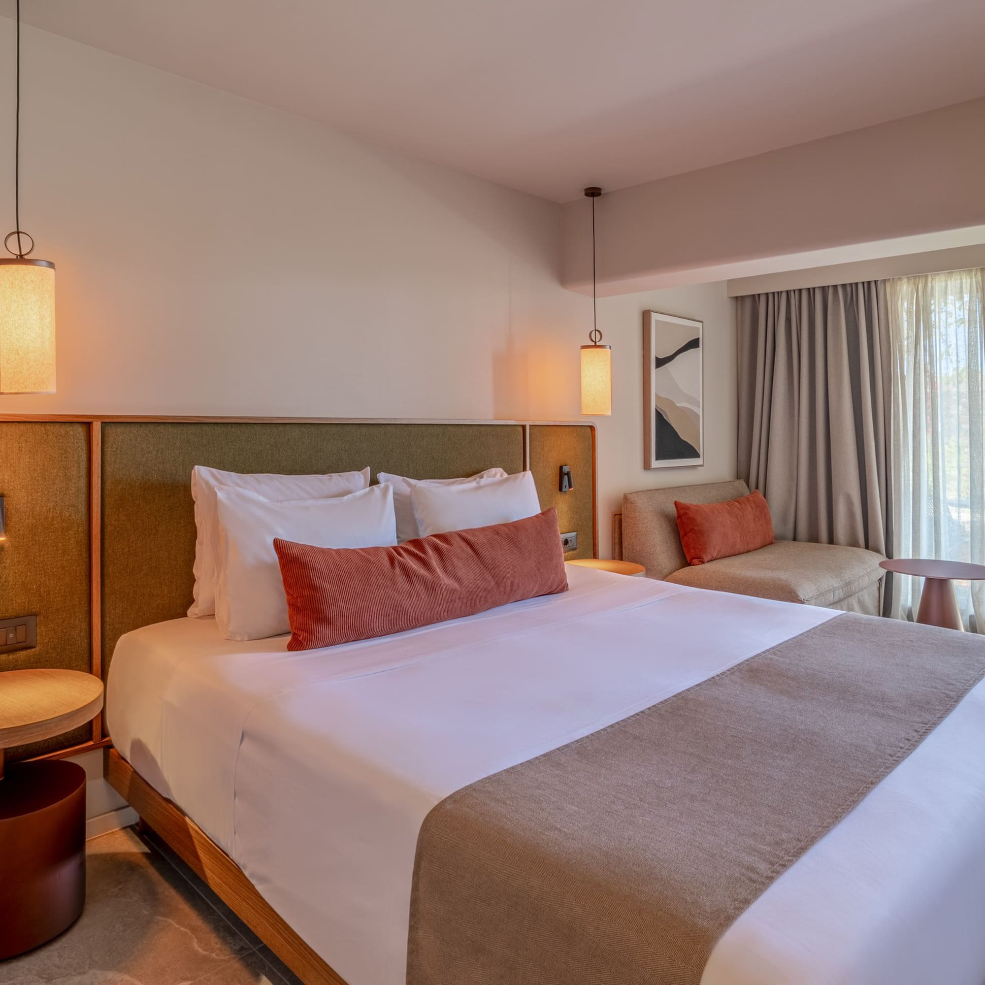 Modern hotel bedroom with king bed, sofa, and patio garden view.