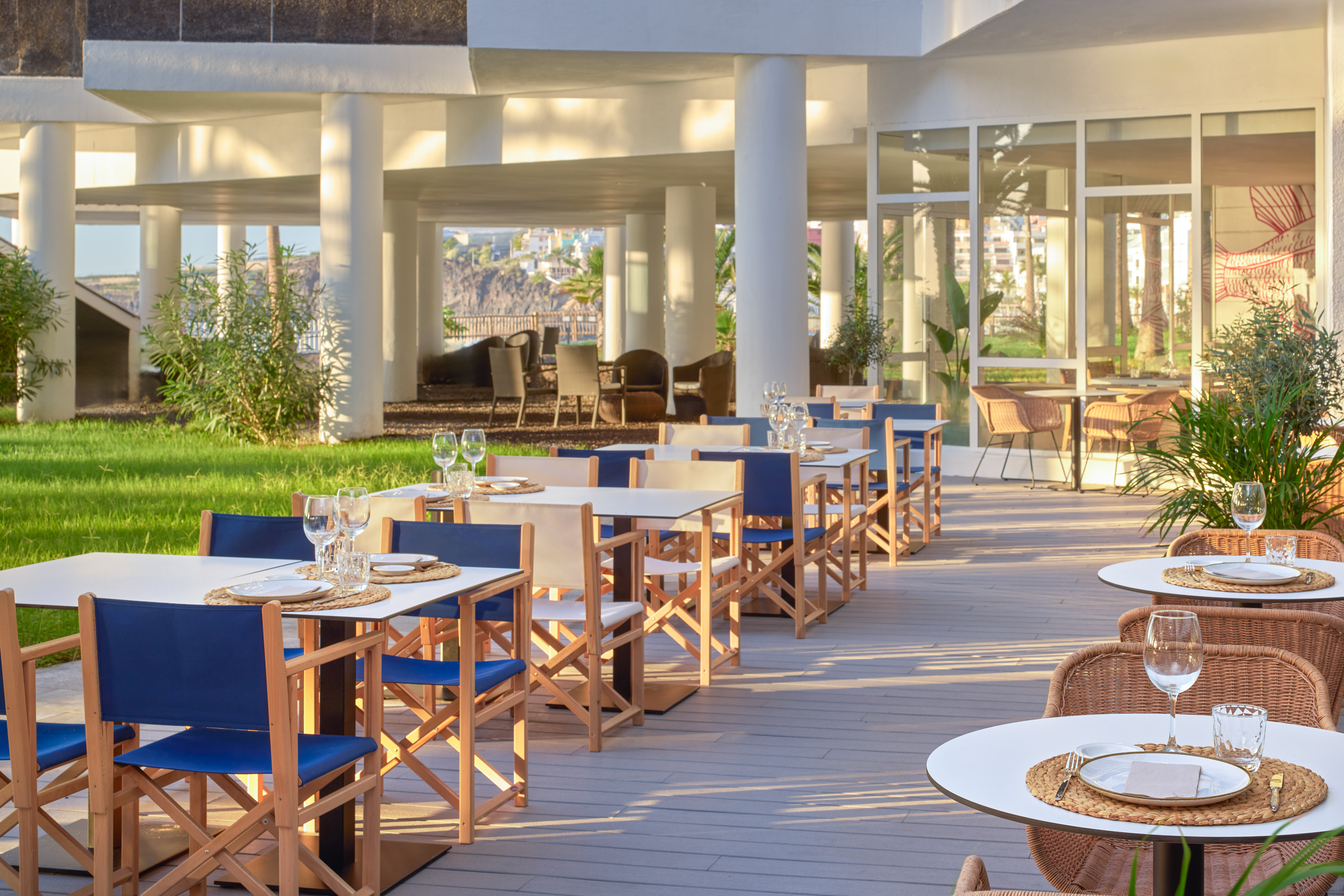Al fresco resort restaurant terrace with set tables and blue chairs.