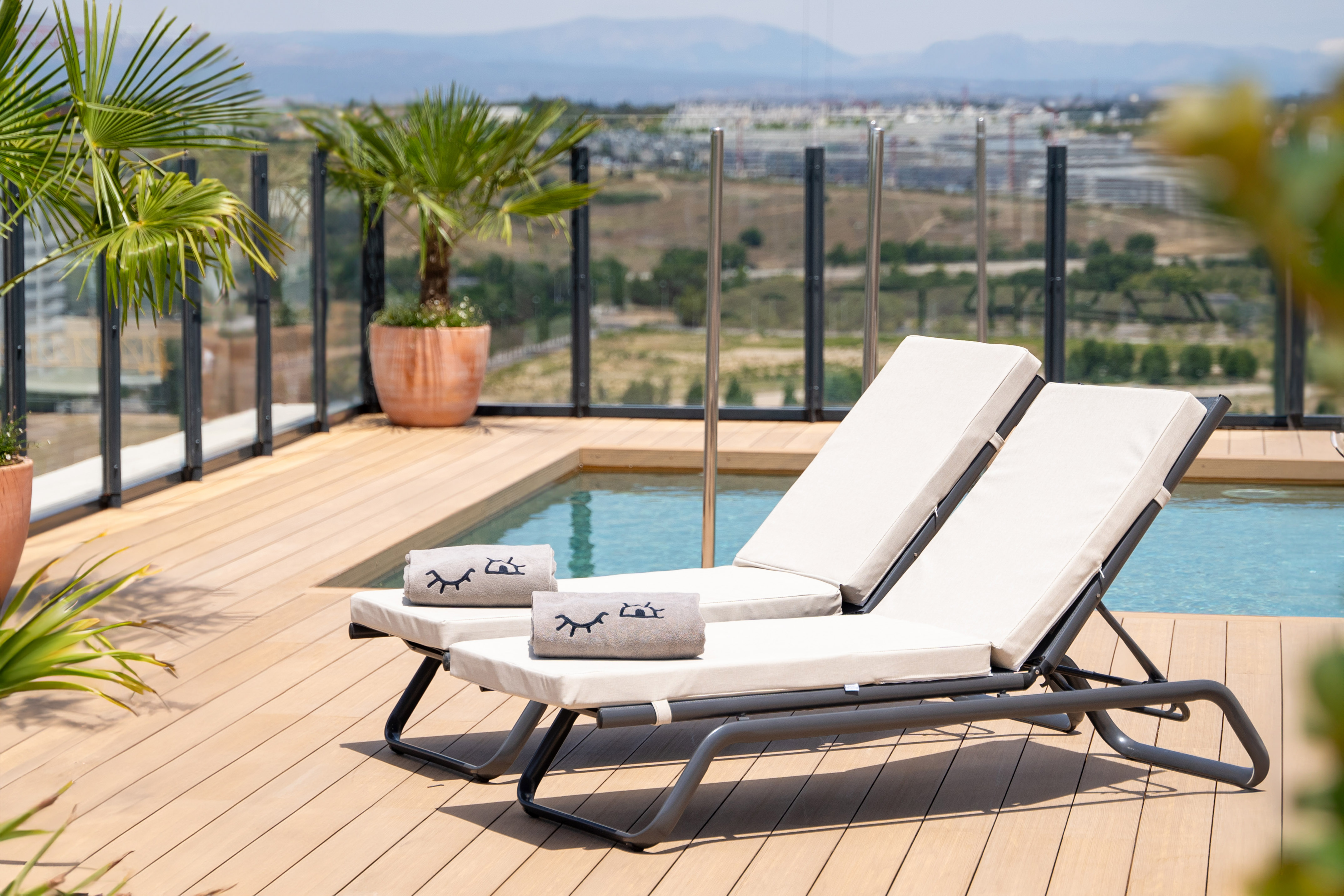Luxury hotel rooftop with lounge chairs, plunge pool, and scenic mountain landscape.