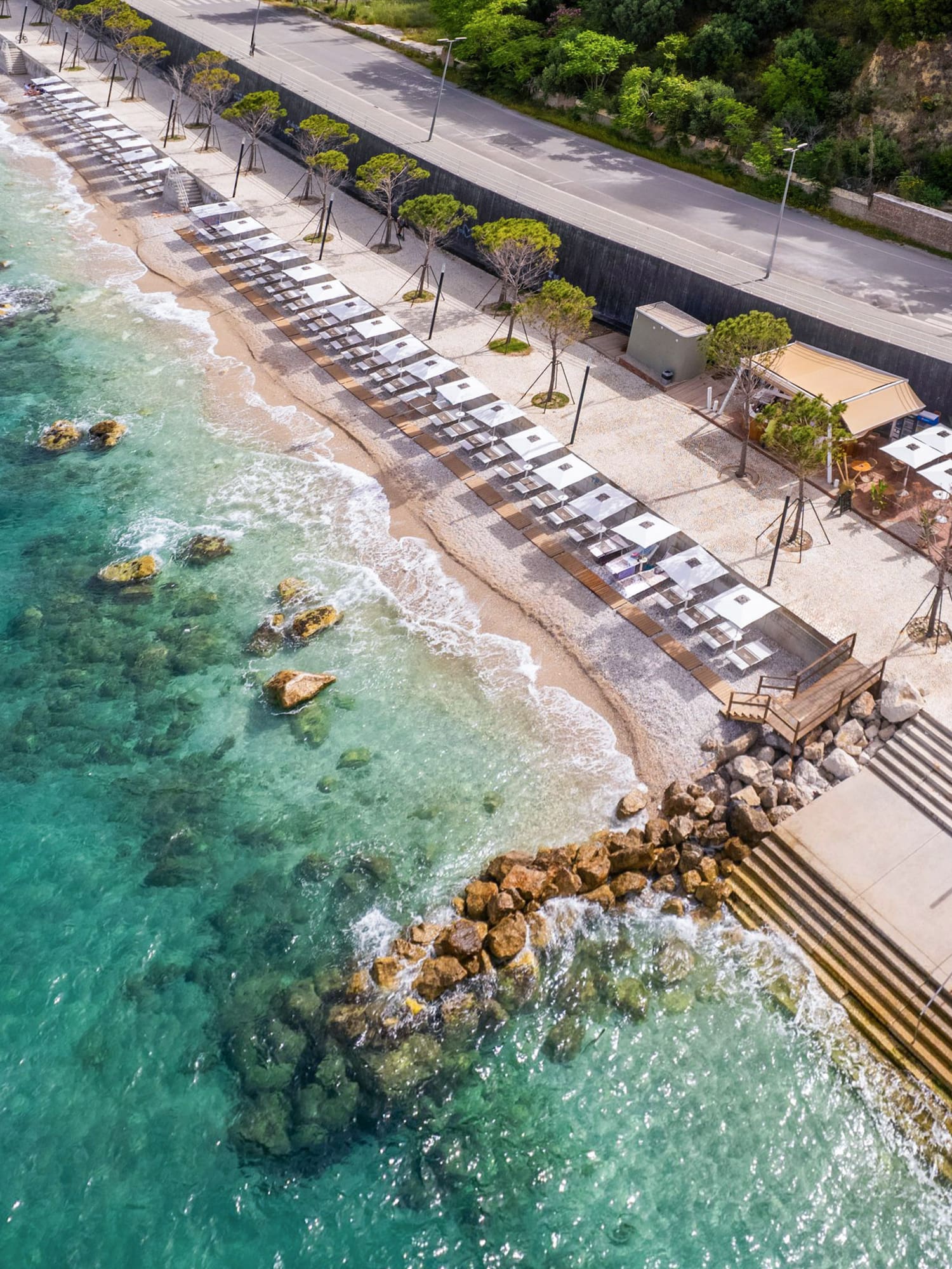 a beach with umbrellas and chairs on the shore
