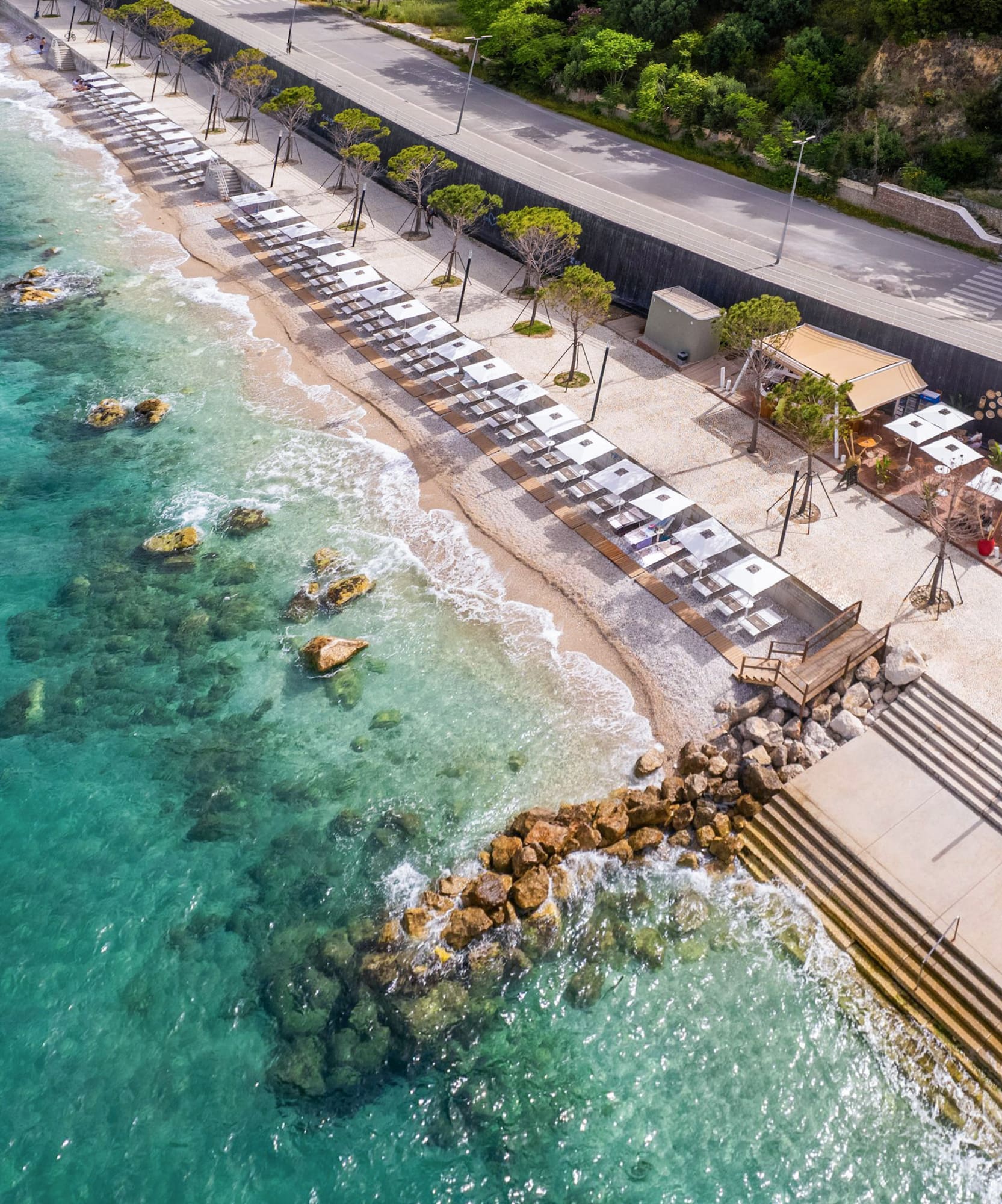 a beach with umbrellas and chairs on the shore