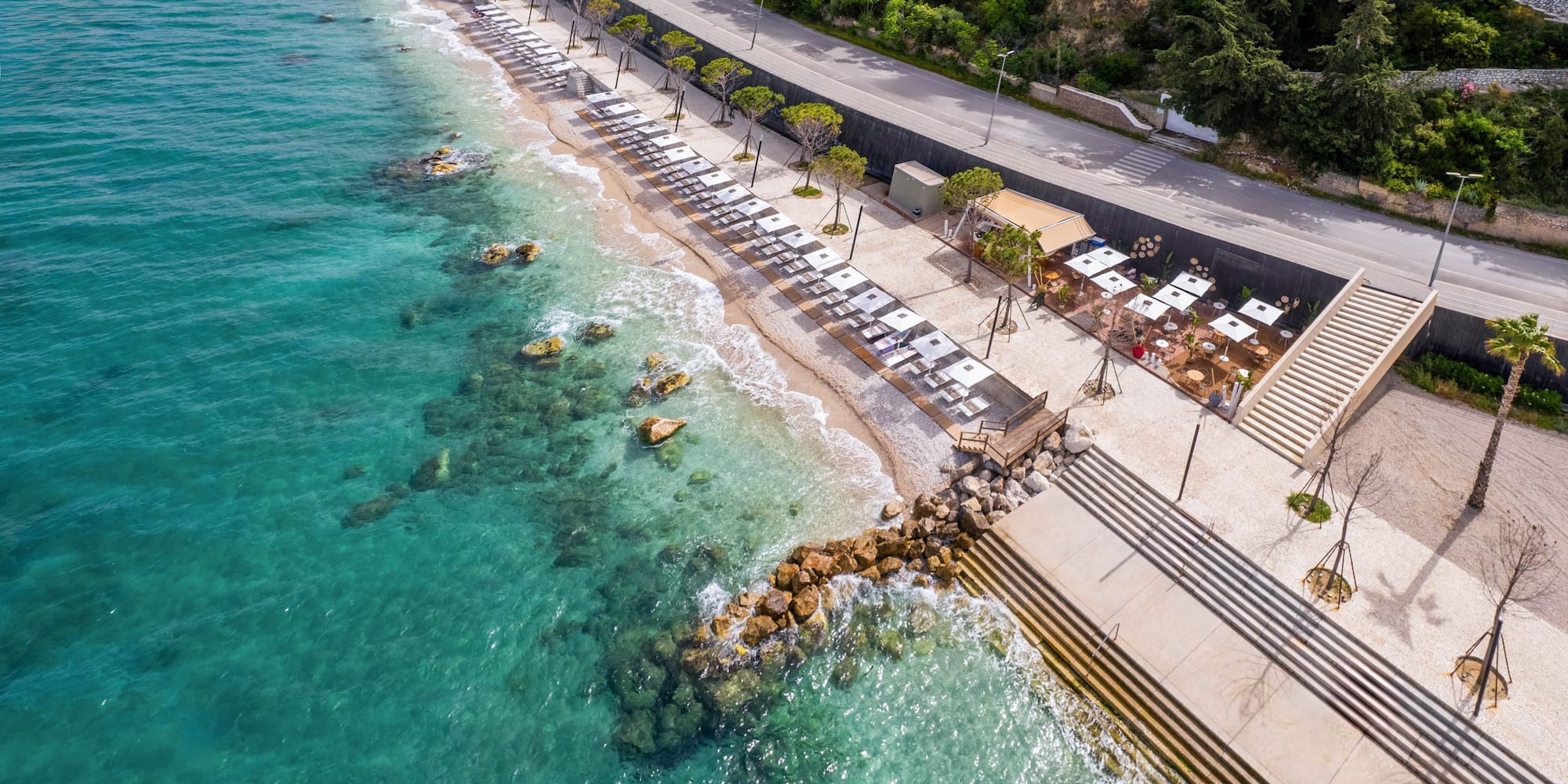 a beach with umbrellas and chairs on the shore
