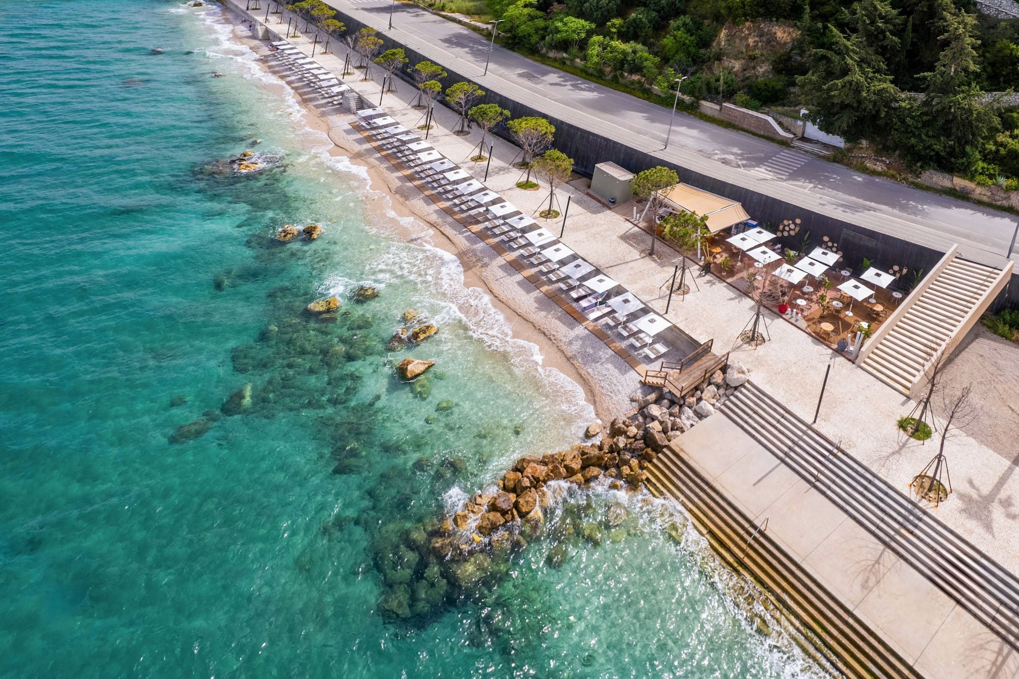 a beach with umbrellas and chairs on the shore