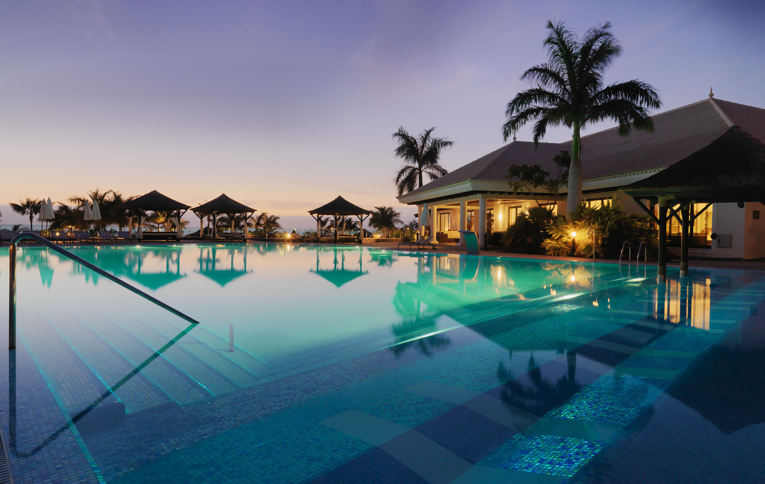 a pool with palm trees and a building