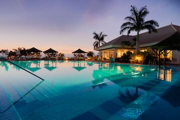 a pool with palm trees and a building