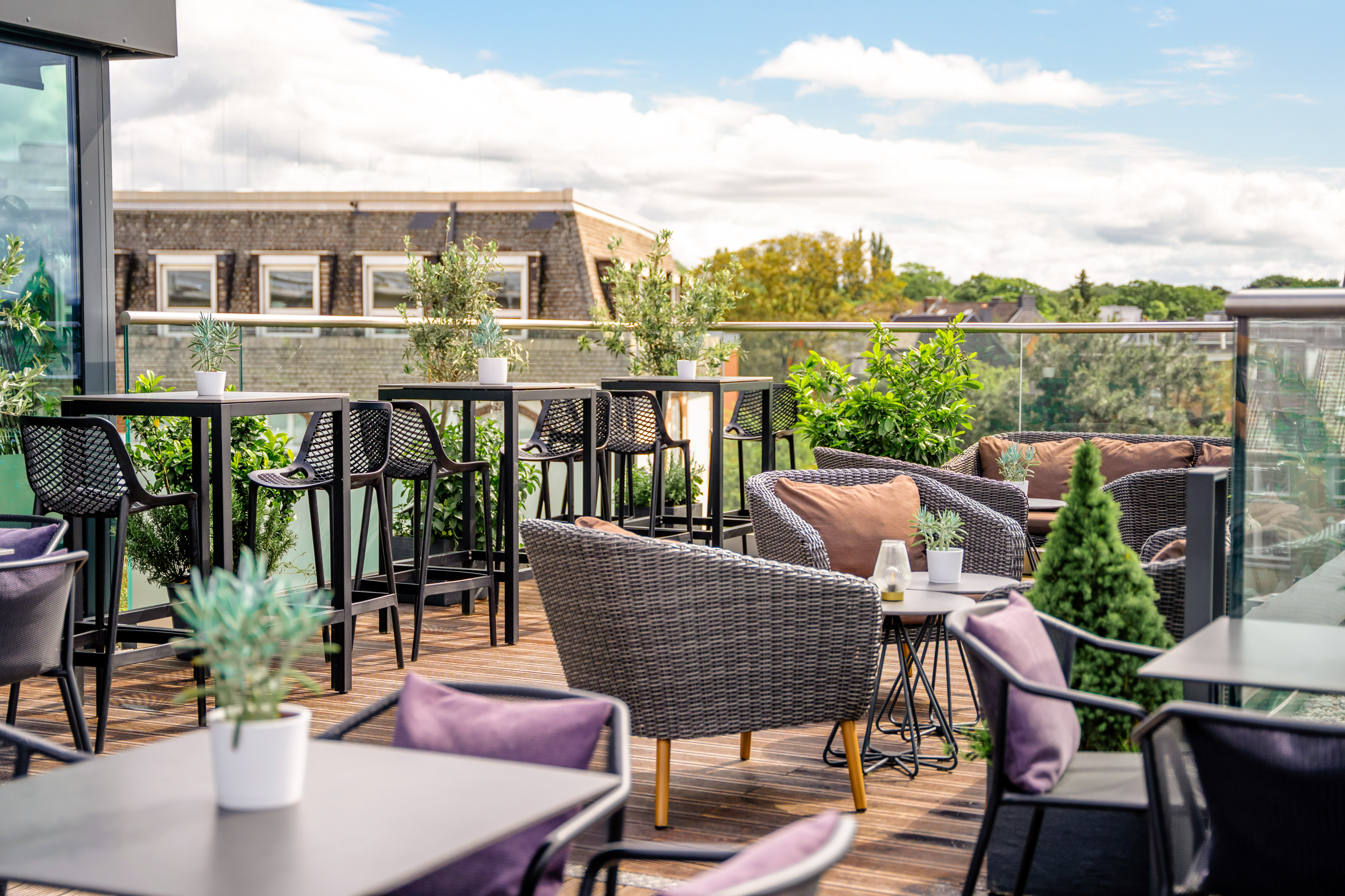 Rooftop bar terrace with contemporary outdoor seating and green plants.