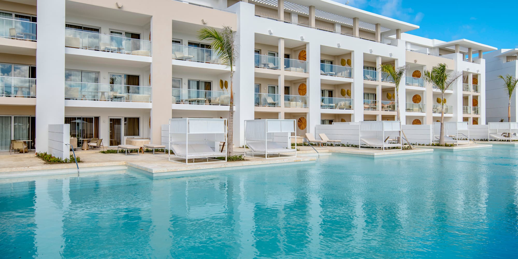 a pool with a building and lounge chairs