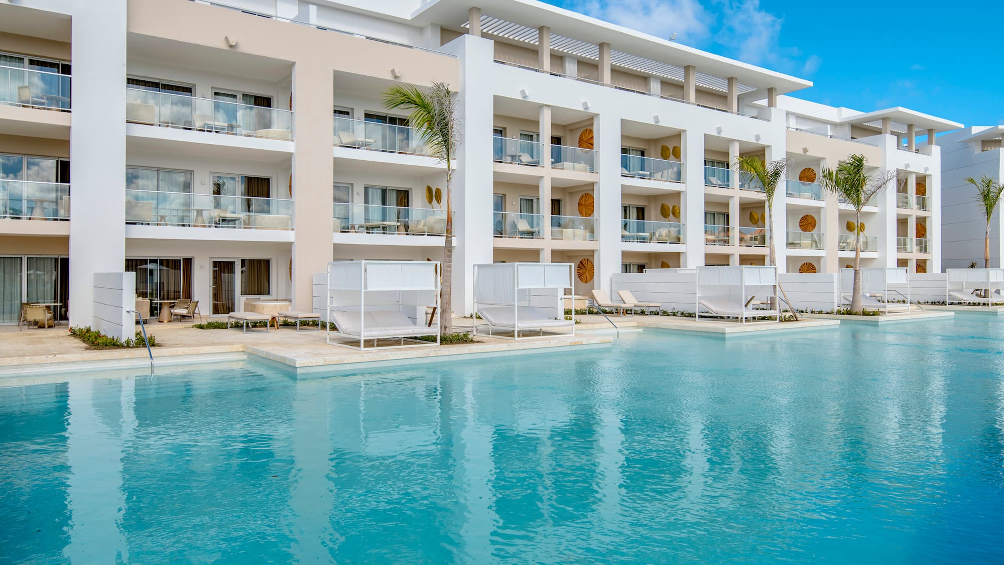 a pool with a building and lounge chairs