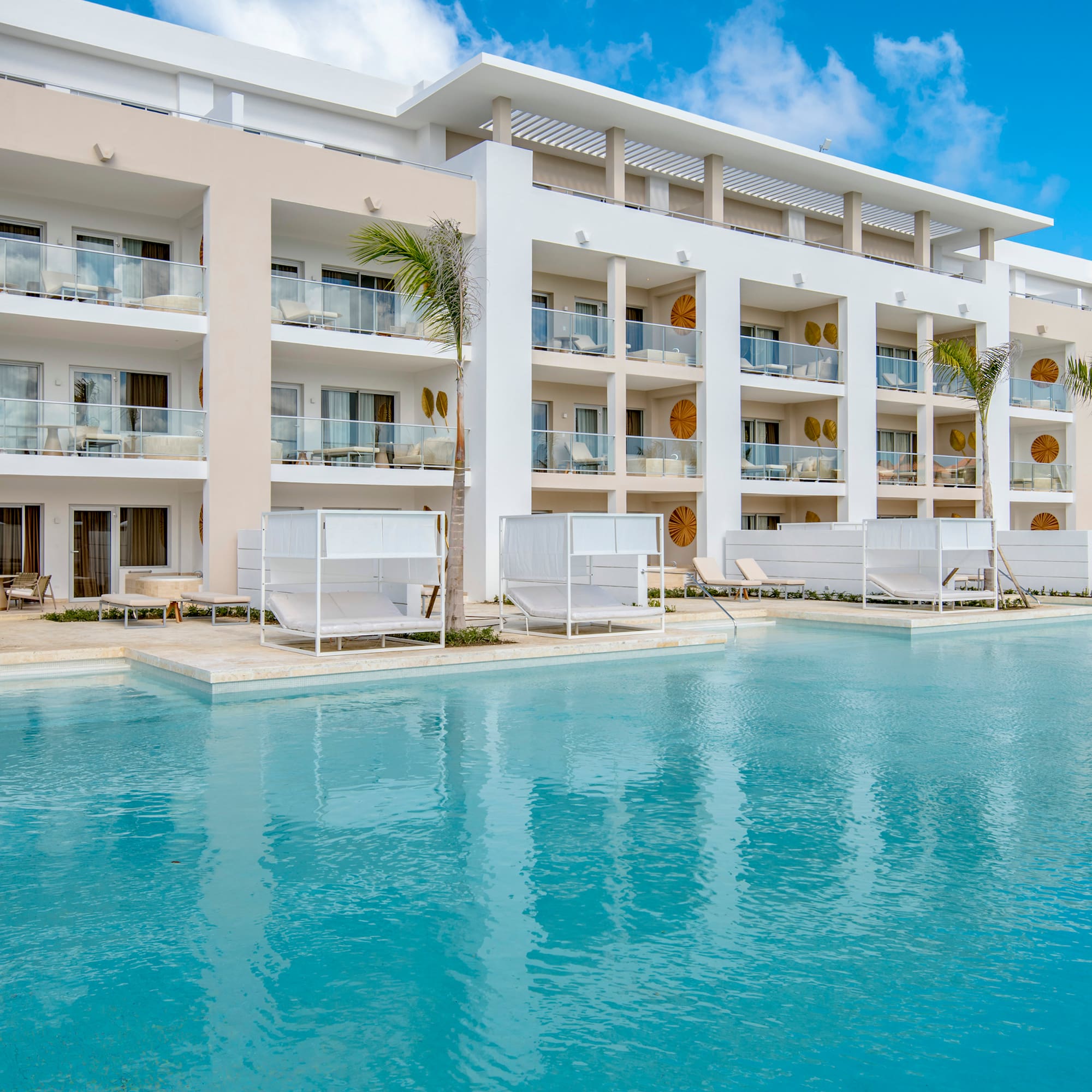 a pool with a building and lounge chairs