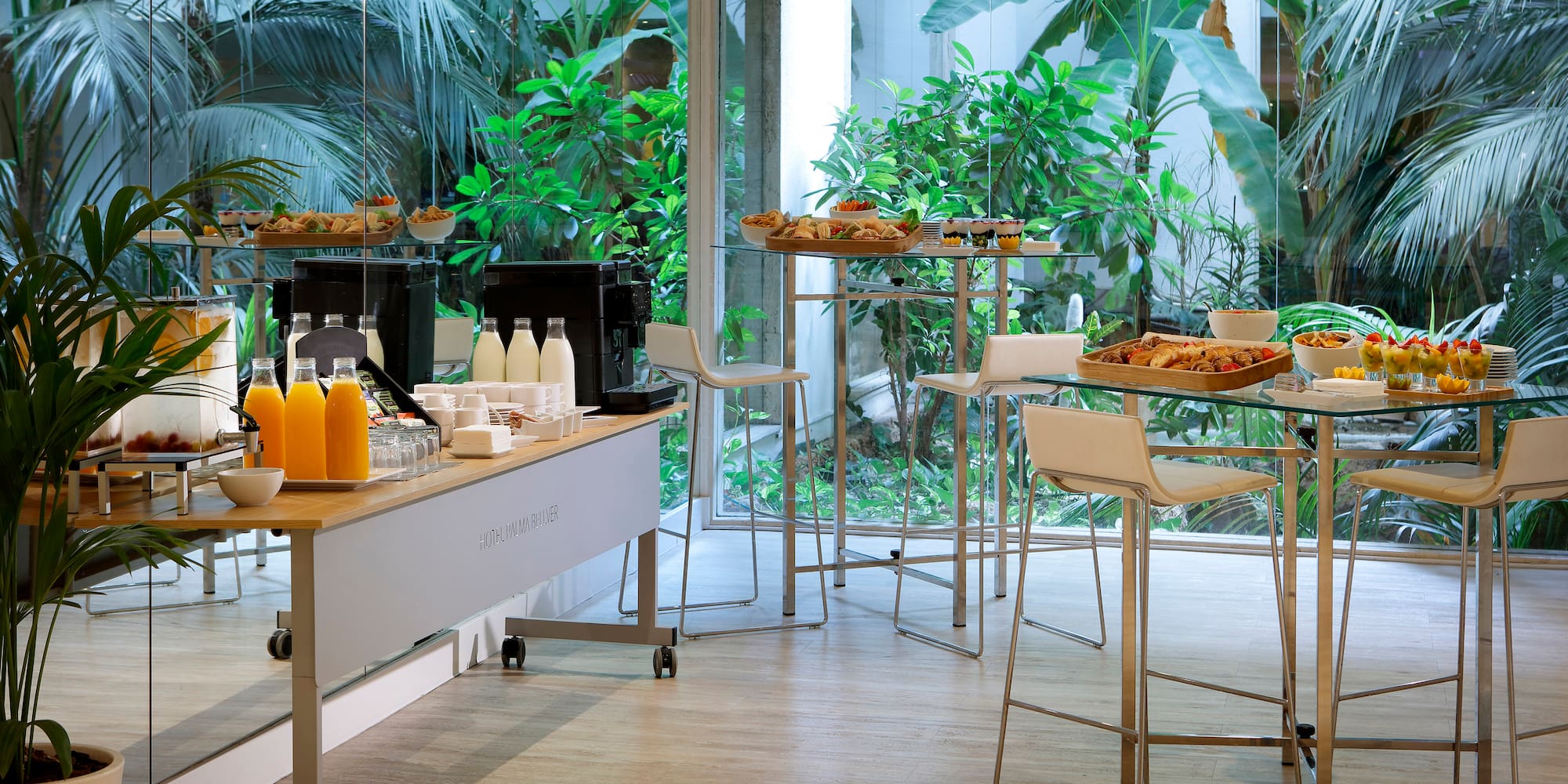 a room with a table and chairs and a glass wall with plants
