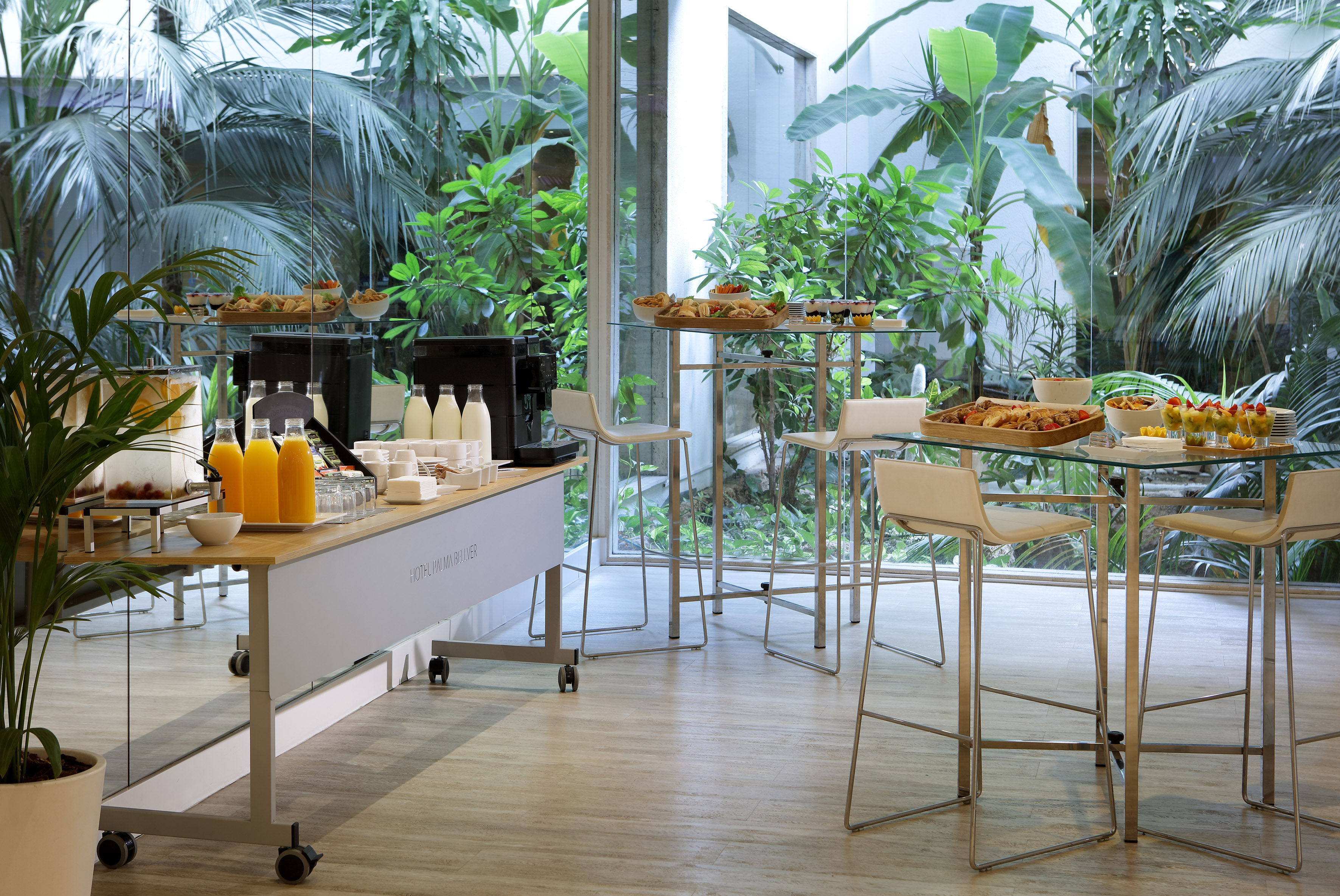 Tropical hotel breakfast buffet with juice, snacks, and lush garden view.