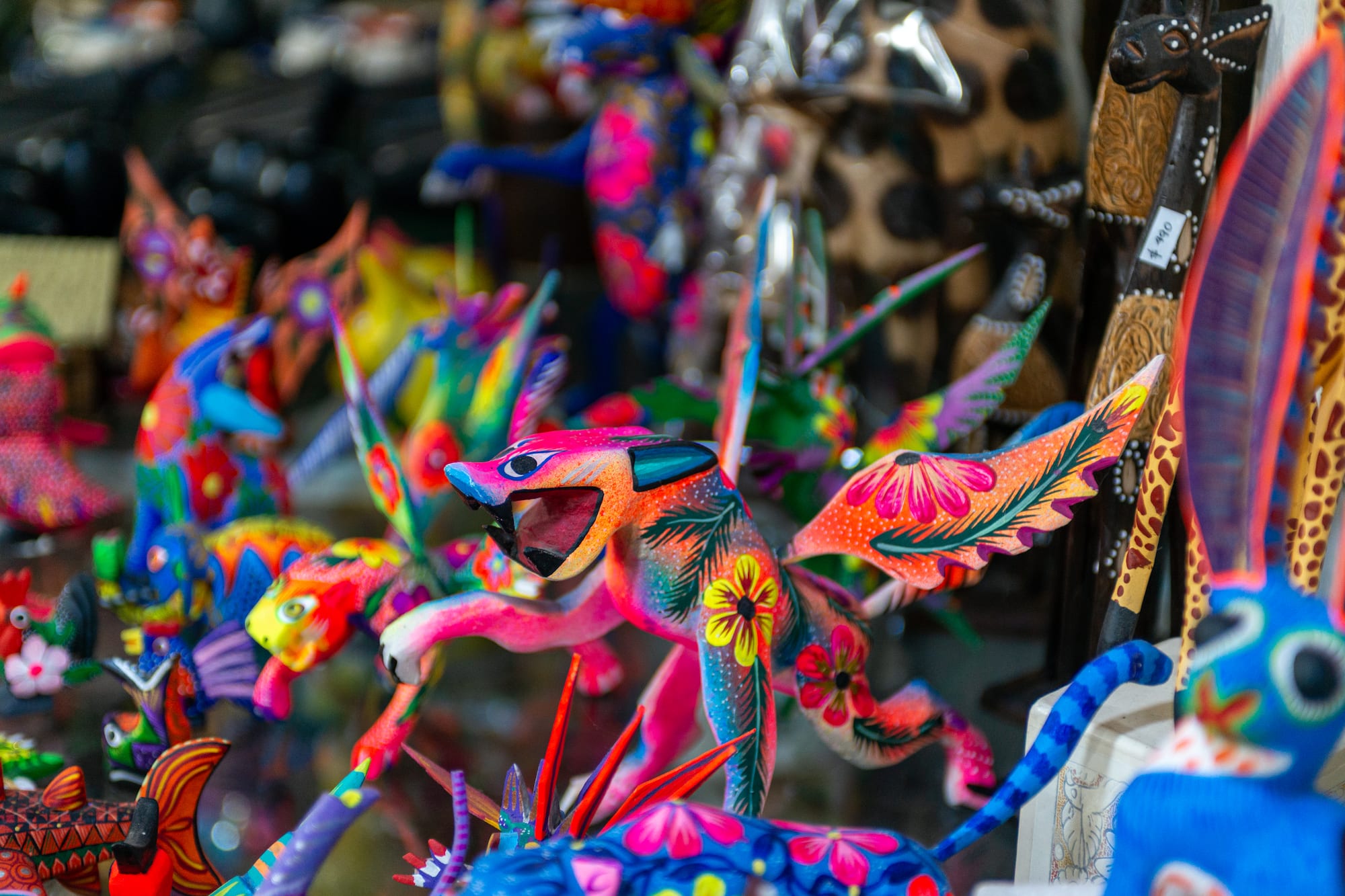 Alebrijes mexicanos vibrantes, figuras de madera tallada con patrones florales.