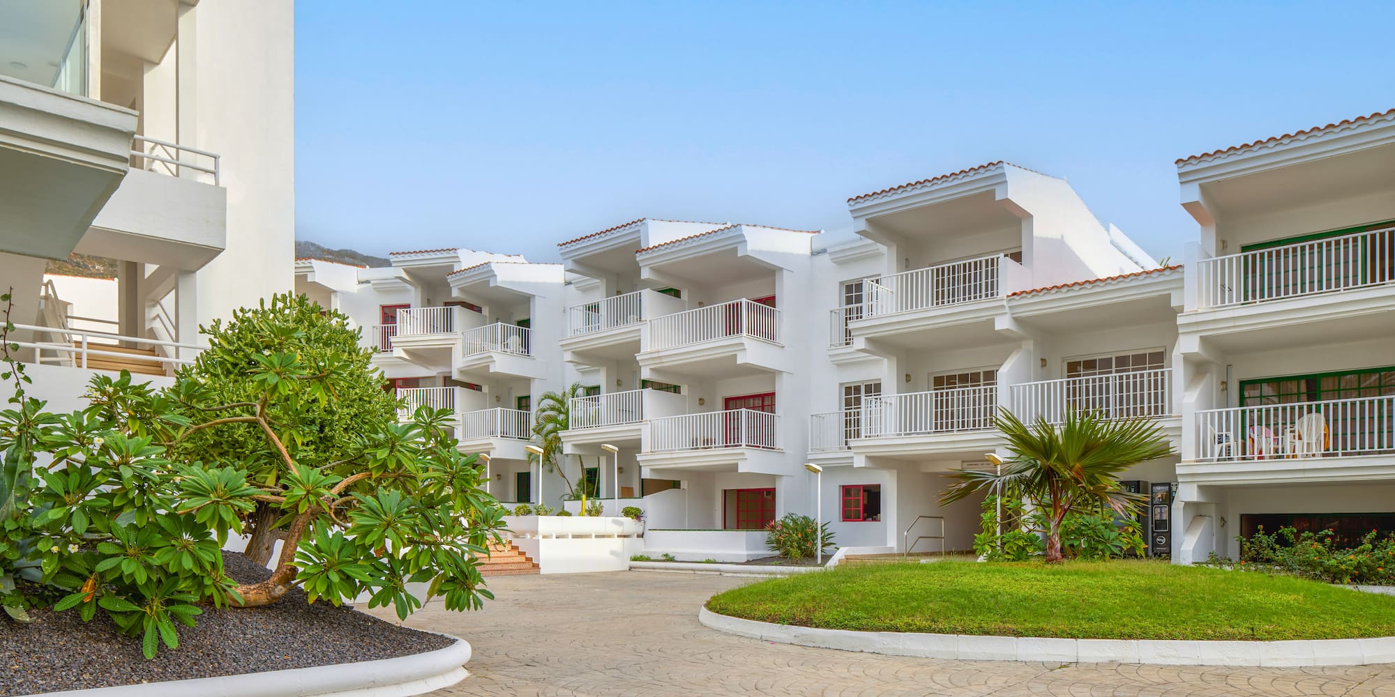 a white building with trees and grass