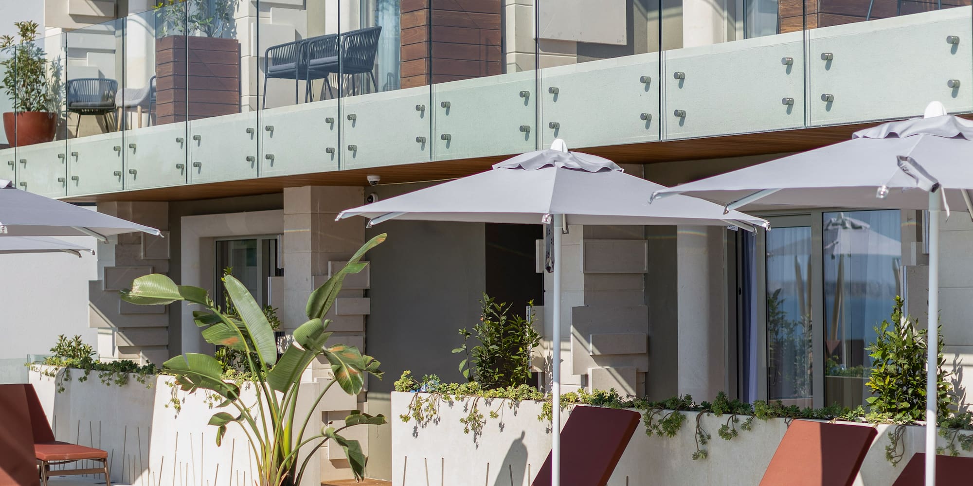 a pool with chairs and umbrellas by a building