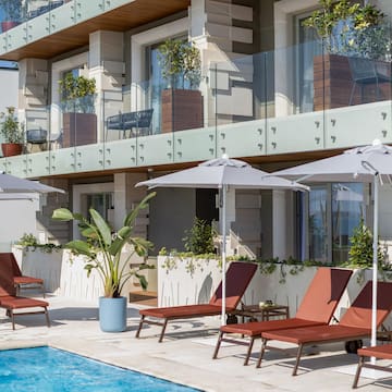 a pool with chairs and umbrellas by a building