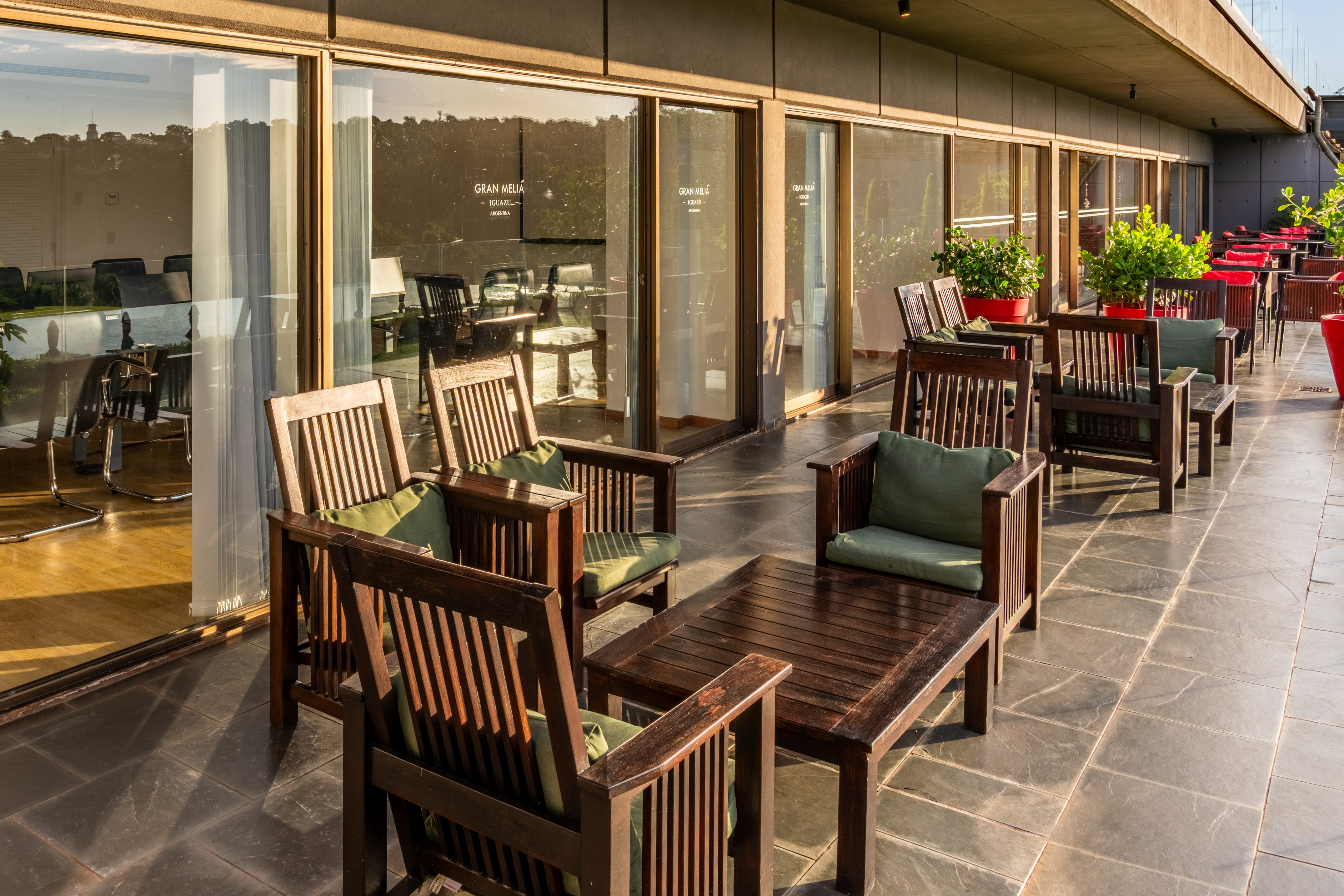 Gran Meliá Iguazú hotel patio with wooden lounge chairs and green cushions.