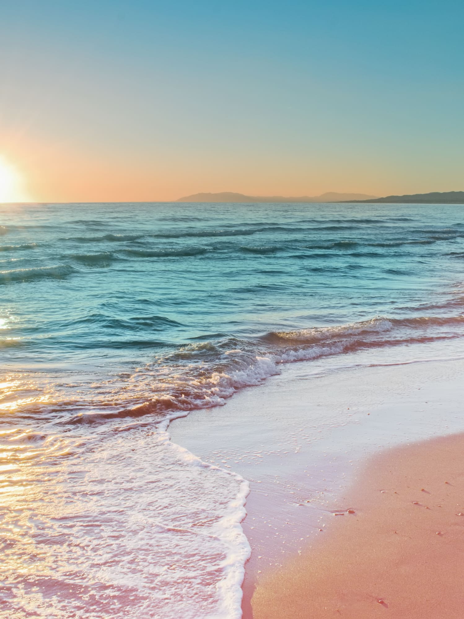 a beach with waves and a sunset