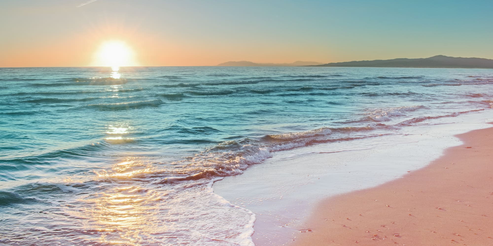 a beach with waves and a sunset